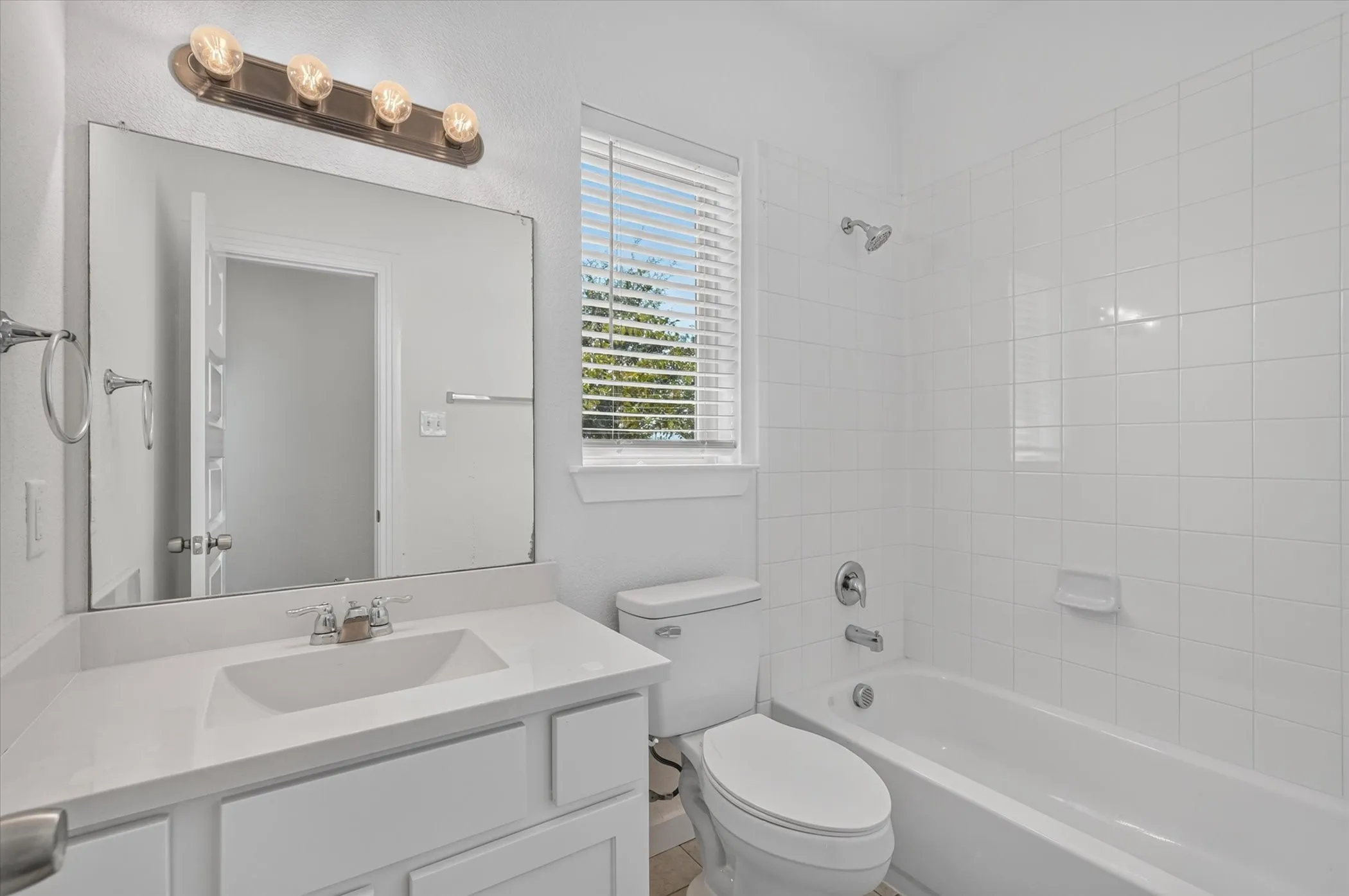Bright and clean bathroom featuring a large framed mirror, white subway tile walls, and a single-basin vanity with ample counter space