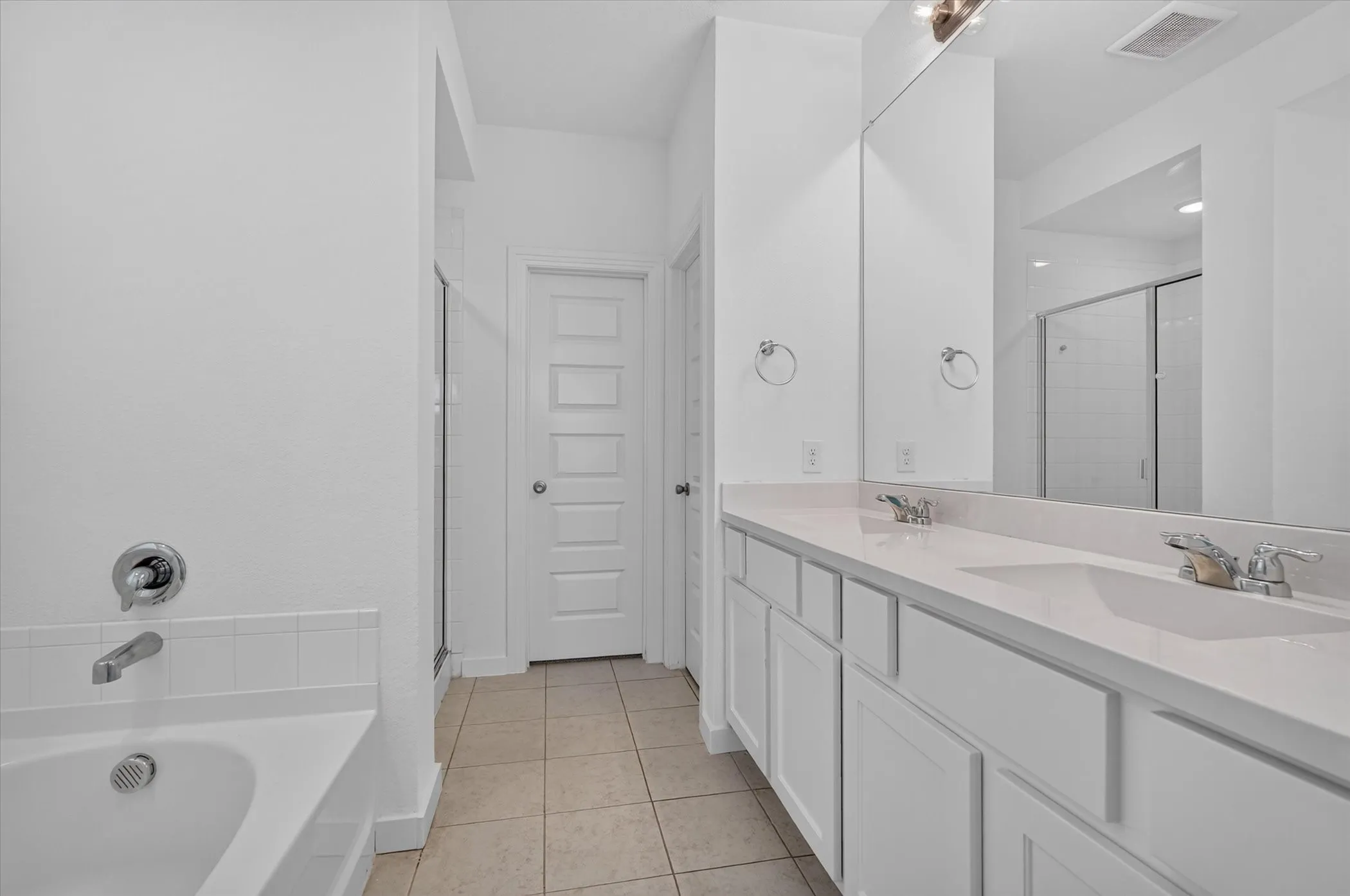 Spacious dual-vanity bathroom featuring a long countertop with integrated sinks, chrome fixtures, and ample mirror surface
