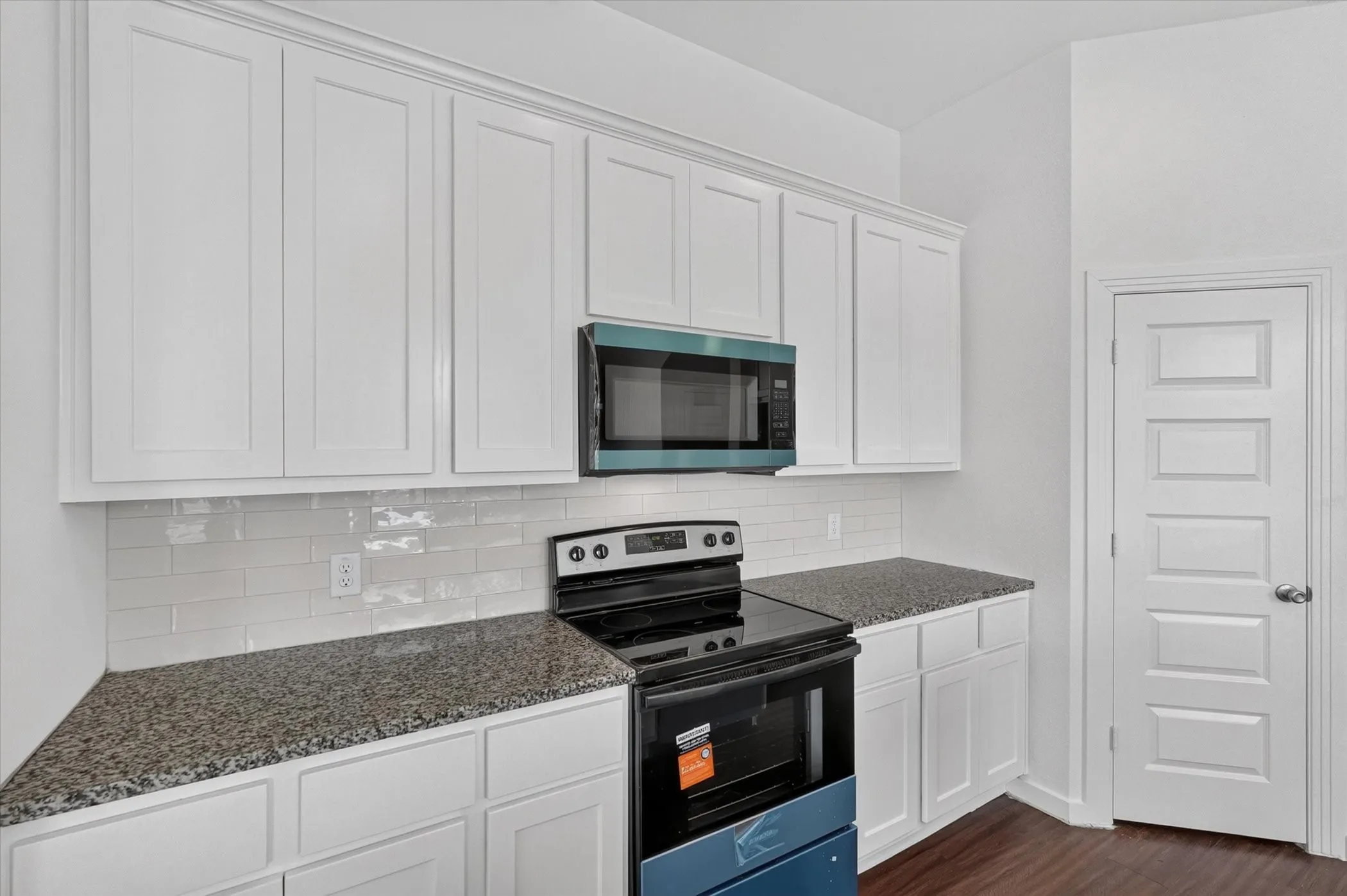Kitchen featuring white shaker-style cabinetry, dark speckled countertops, and a white subway tile backsplash