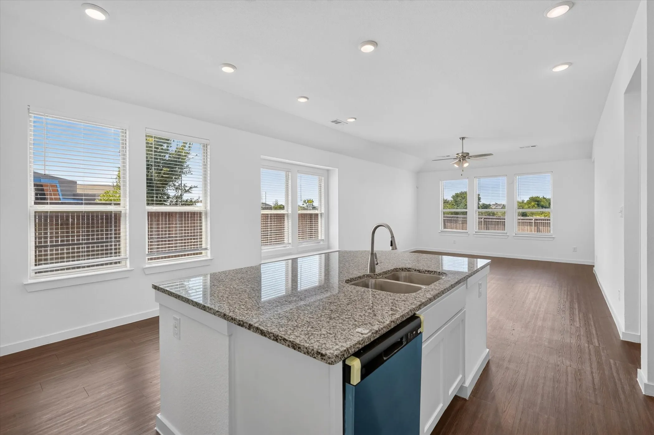 Chef's kitchen featuring a large center island with granite countertop, stainless steel sink with gooseneck faucet, white cabinetry, and dark blue island base
