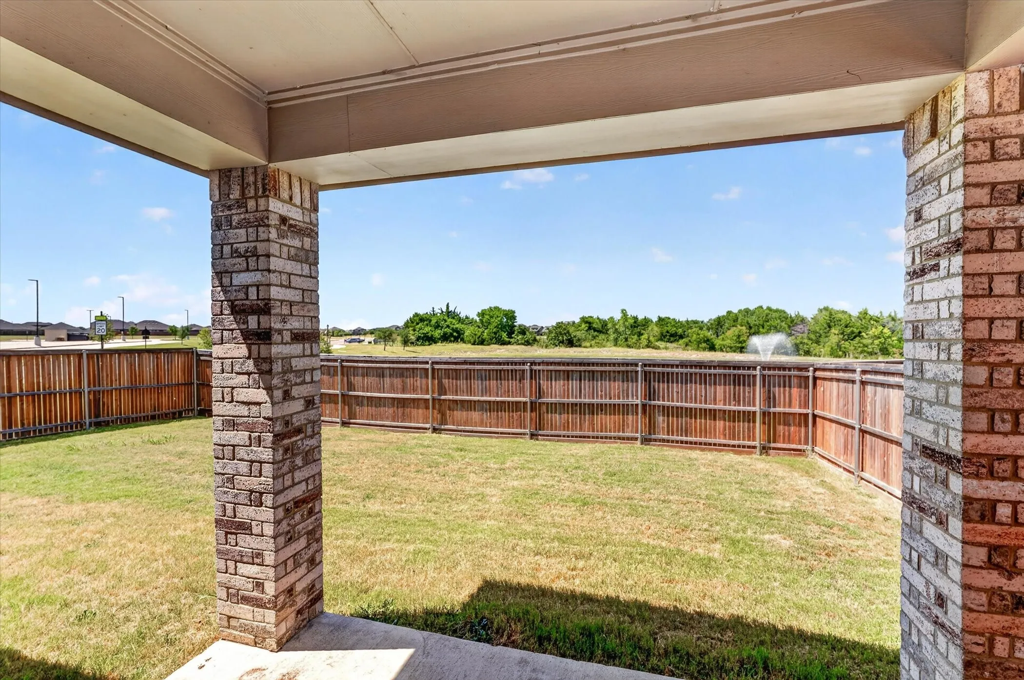 Covered patio featuring brick columns and a concrete slab