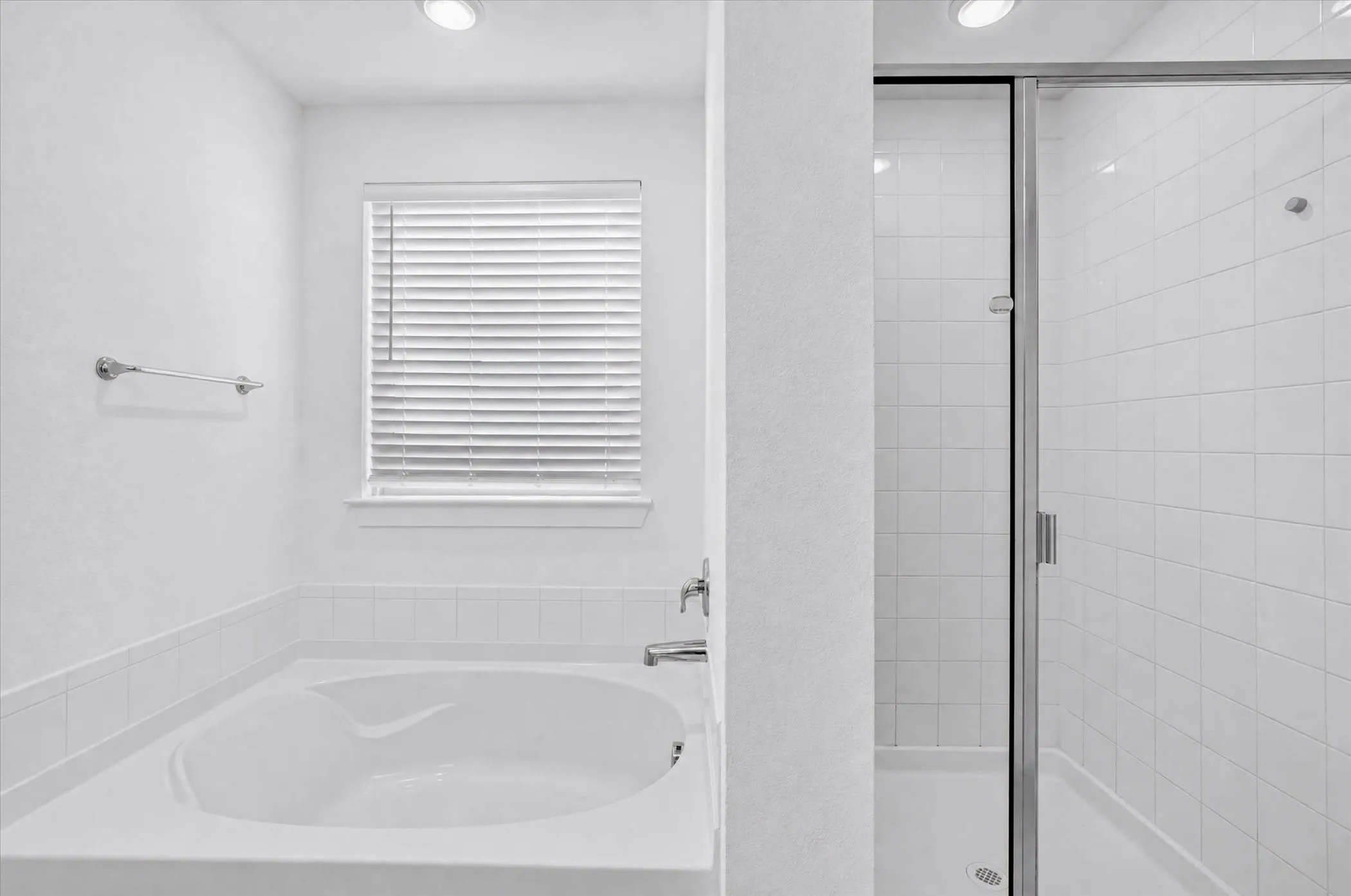 Spa-inspired primary bathroom featuring a deep soaking tub with integrated armrests, white subway tile surround, recessed ceiling lighting, and a frameless glass-enclosed shower stall with chrome hardware