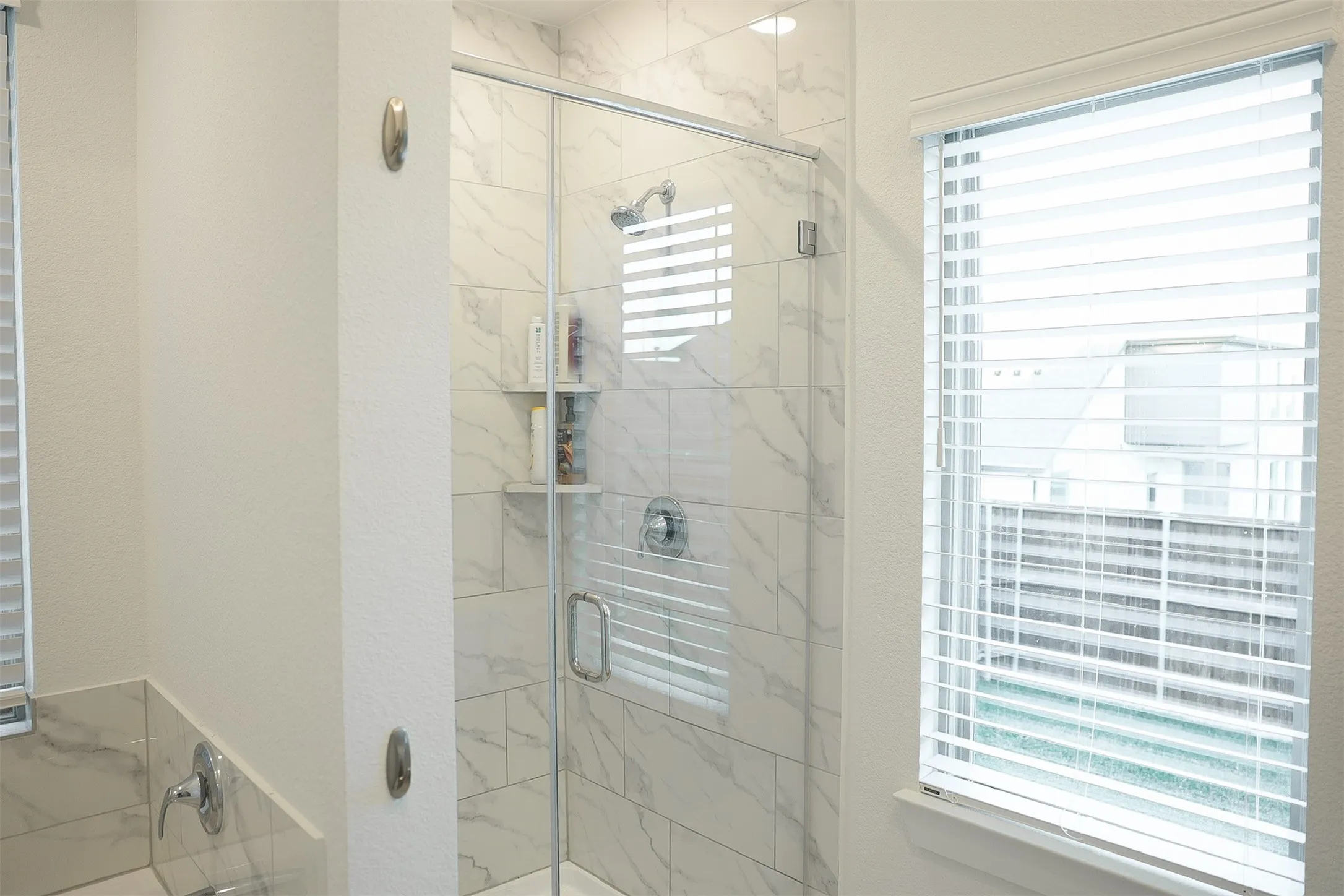 Contemporary walk-in shower featuring a frameless glass enclosure and white marble-look tile surround