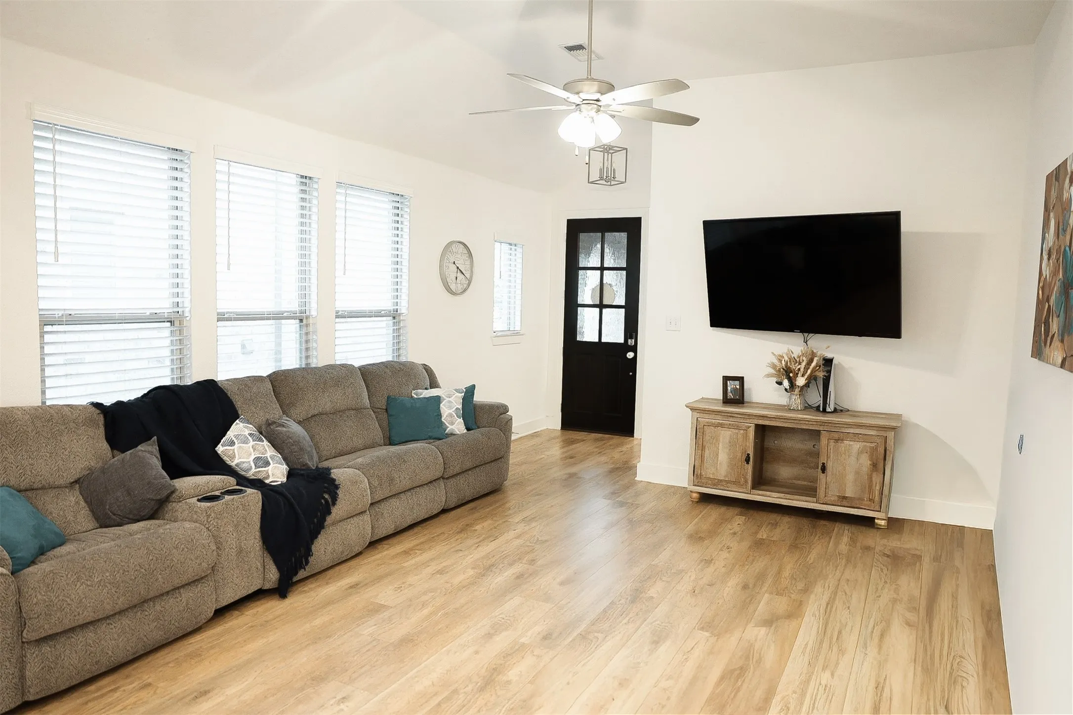 Spacious living area featuring wood-finish flooring, vaulted ceilings, and recessed lighting