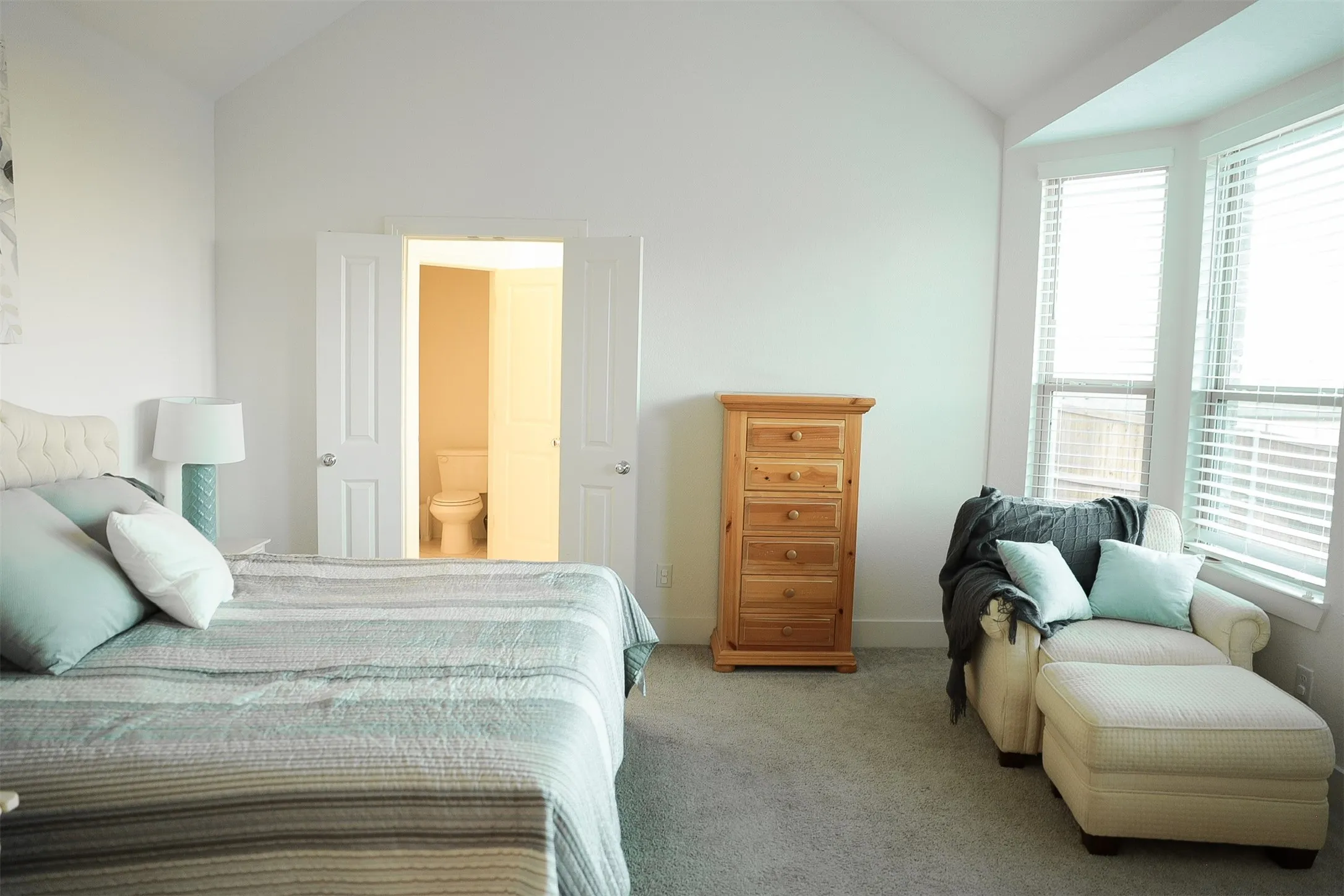 Carpeted room featuring a vaulted ceiling and a bay window with blinds