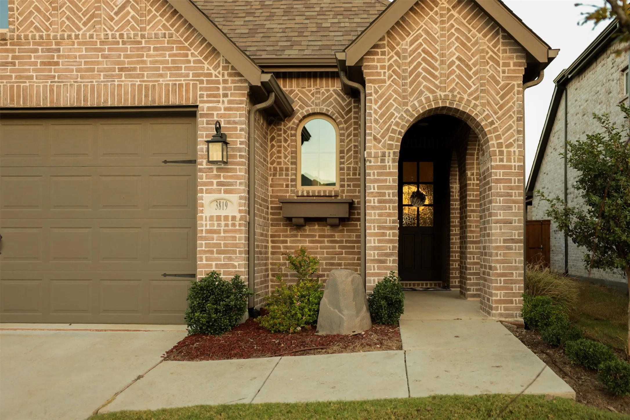 Brick exterior featuring a herringbone pattern accenting the arched entryway