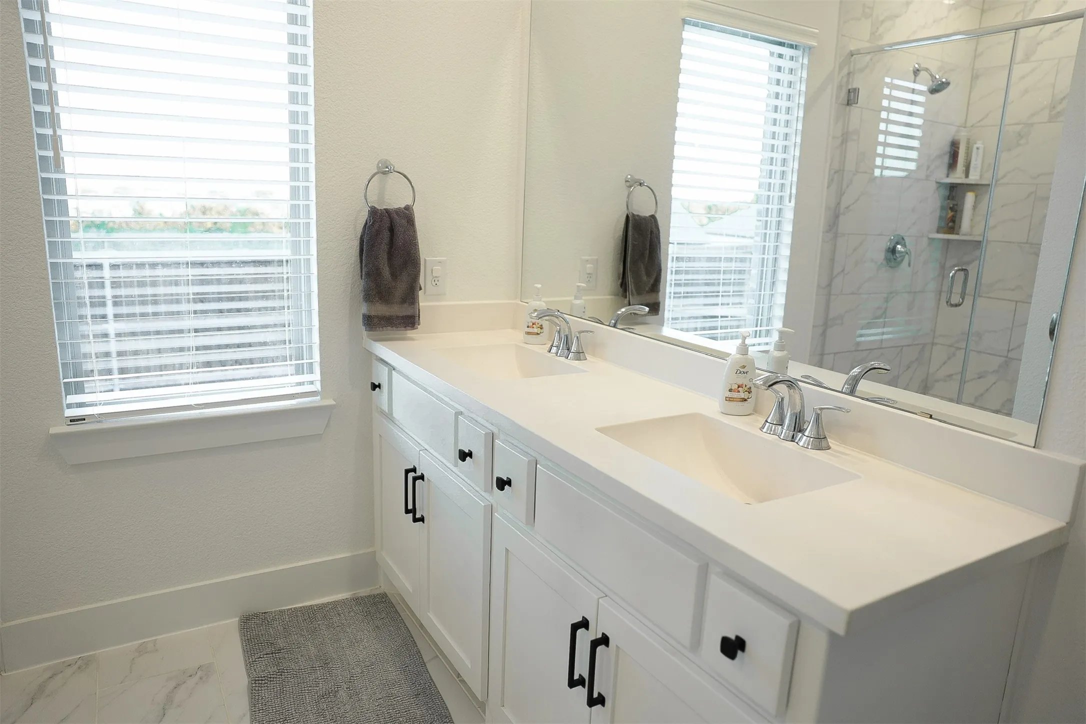 Dual vanity with integrated sinks, white cabinetry, and matte black hardware