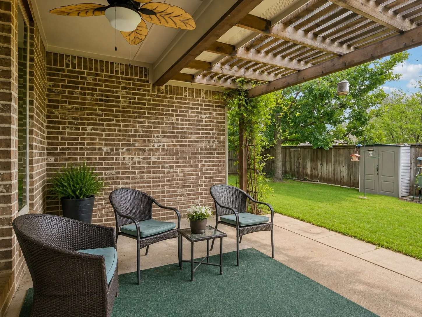 Covered patio featuring a brick exterior, concrete flooring, and a decorative ceiling fan