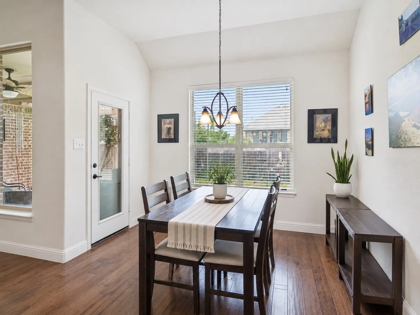 Dining area featuring wood-finish flooring, a vaulted ceiling, and a rear-entry glass-paneled door