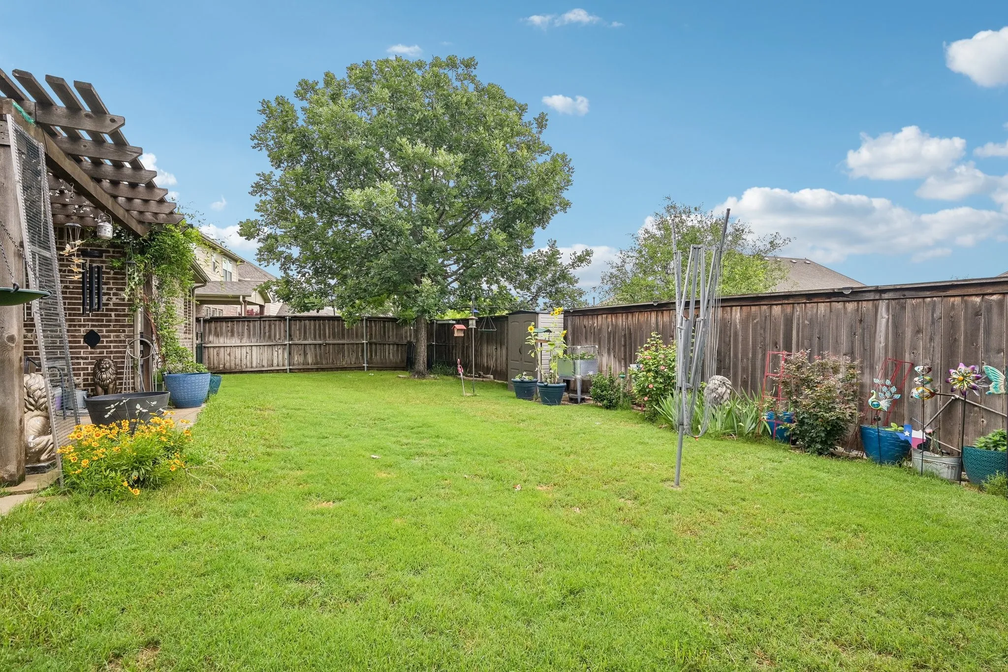 Expansive backyard featuring a manicured lawn, a full privacy fence, and mature trees