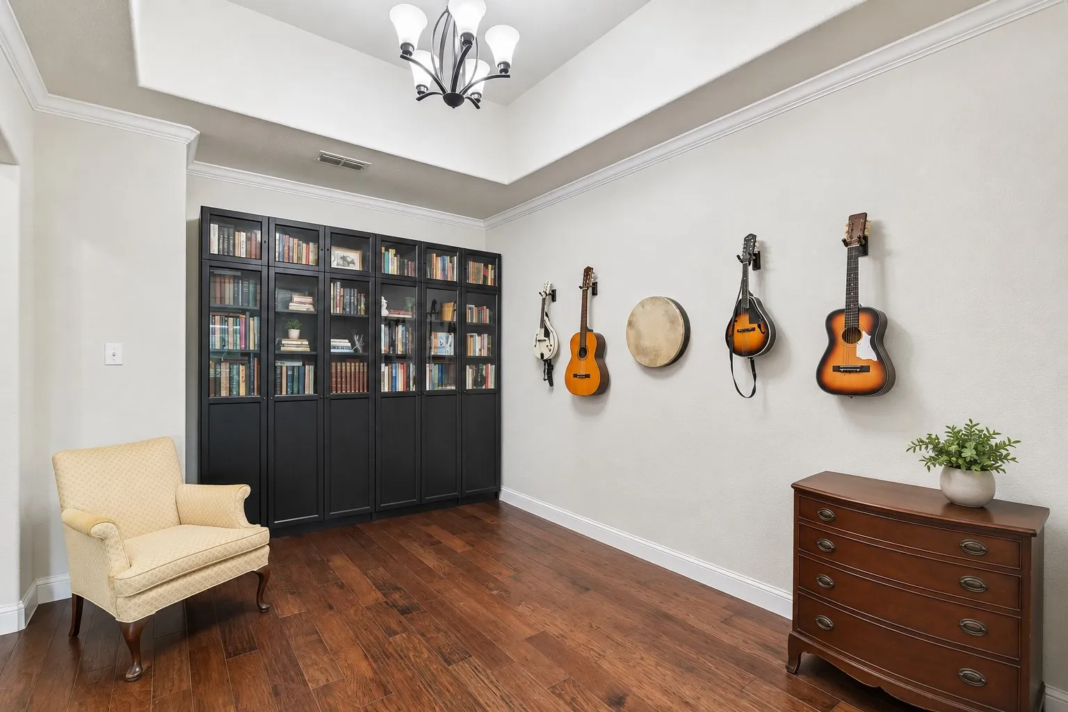 Spacious dining room featuring rich wood-finish flooring, a full wall of built-in cabinetry with glass panel doors, and a decorative tray ceiling