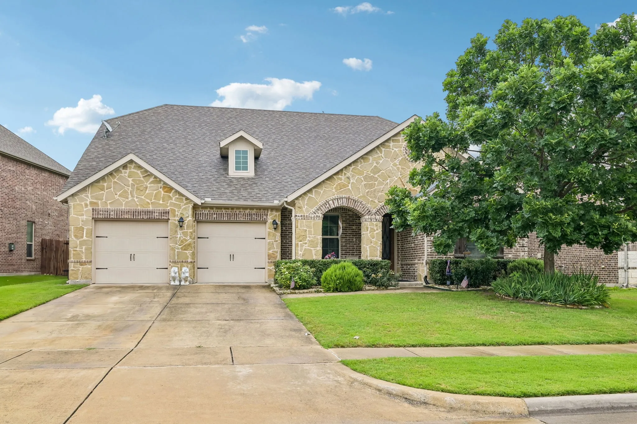 Stone and brick exterior with a covered front patio and three-car garage