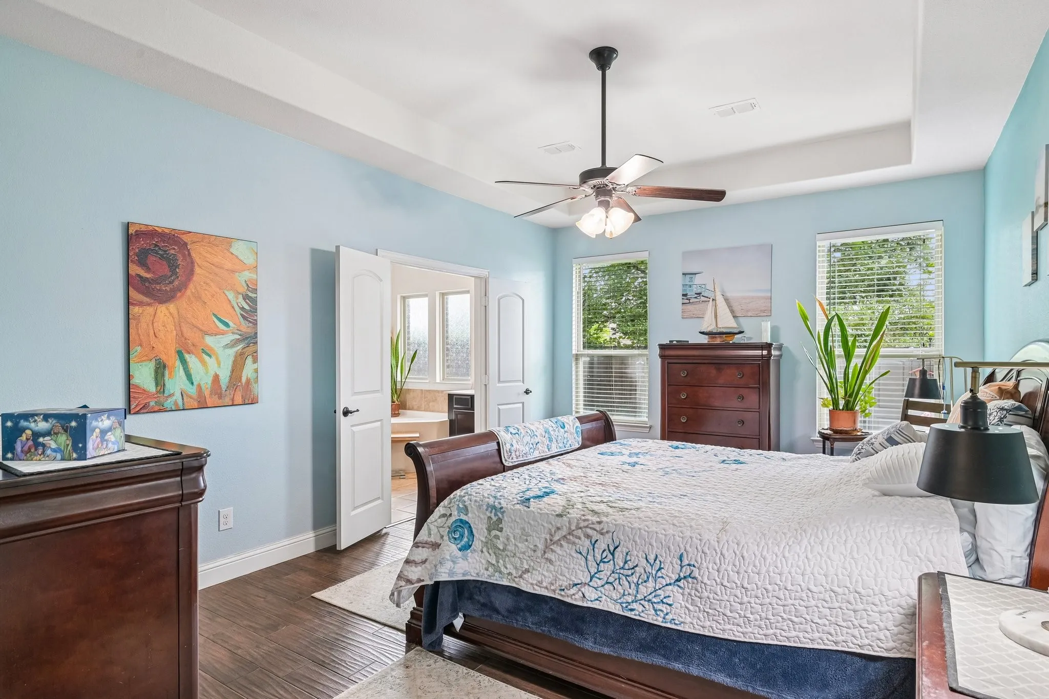 Tray ceiling with a ceiling fan, recessed lighting, and wood-finish flooring