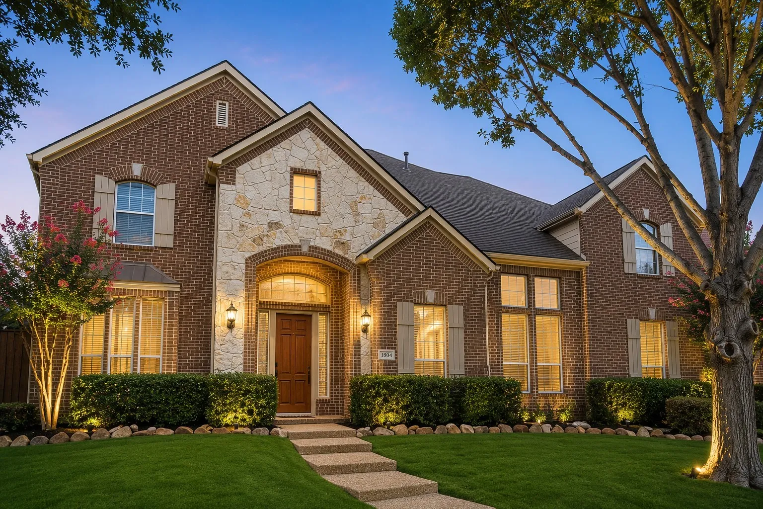 Two-story brick and stone facade residence featuring an arched entry with a solid wood door