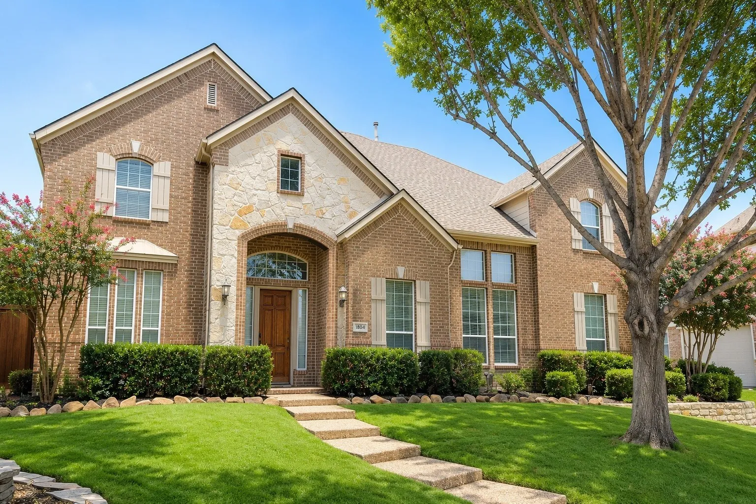 Brick and stone exterior featuring an arched entry, wood door, multiple gables, and decorative shutters