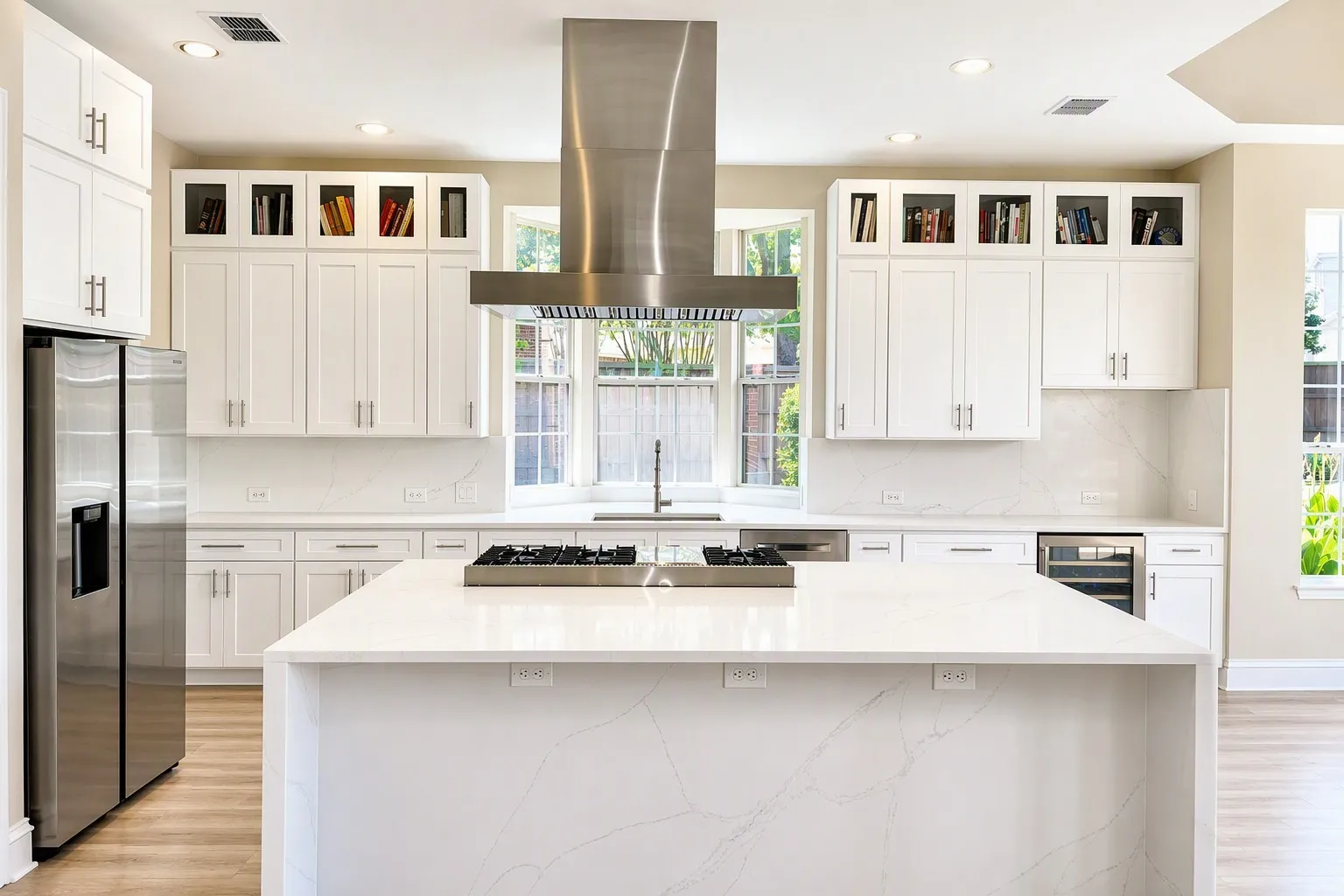 Contemporary kitchen featuring a large central island, white cabinetry, integrated stainless steel appliances, and wood-finish flooring