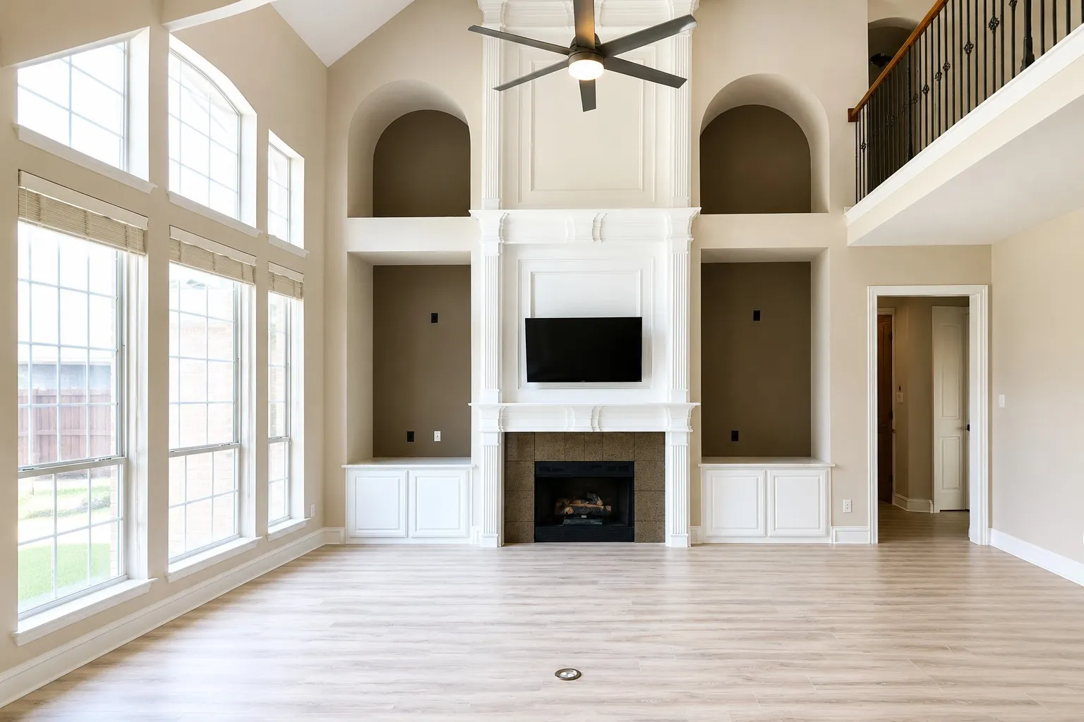 Living area featuring a vaulted ceiling with a ceiling fan, a fireplace with a mantel, built-in cabinetry, and wood-finish flooring