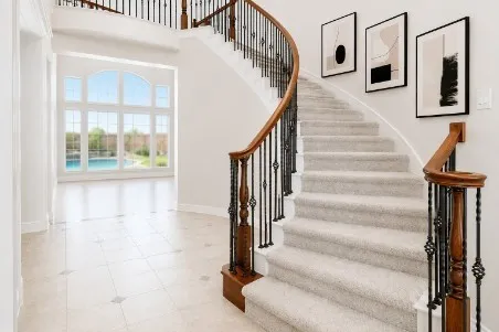 Grand curved staircase featuring wood handrails and wrought iron balusters