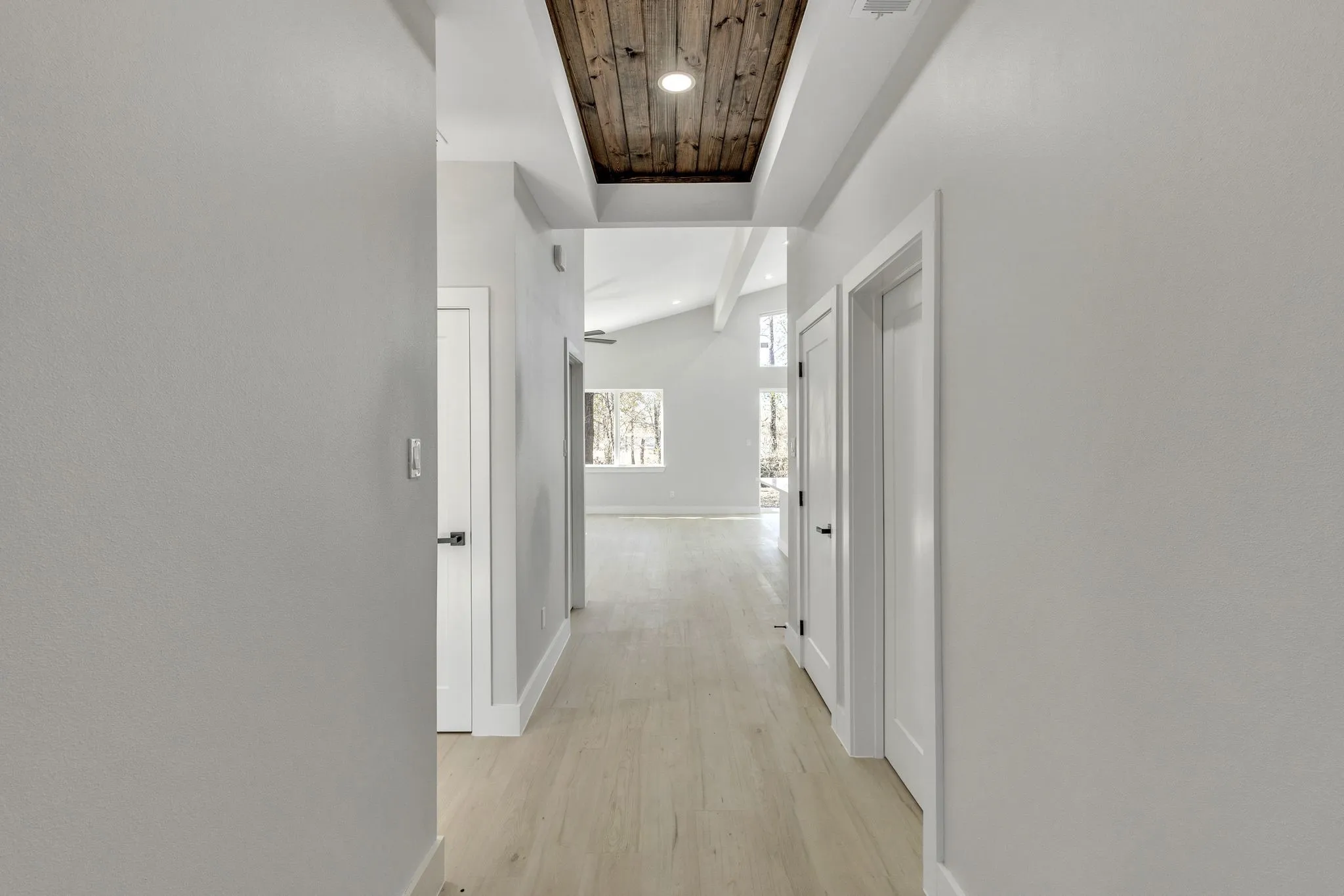 Corridor with wood ceiling, vaulted ceiling, and light hardwood / wood-style floors