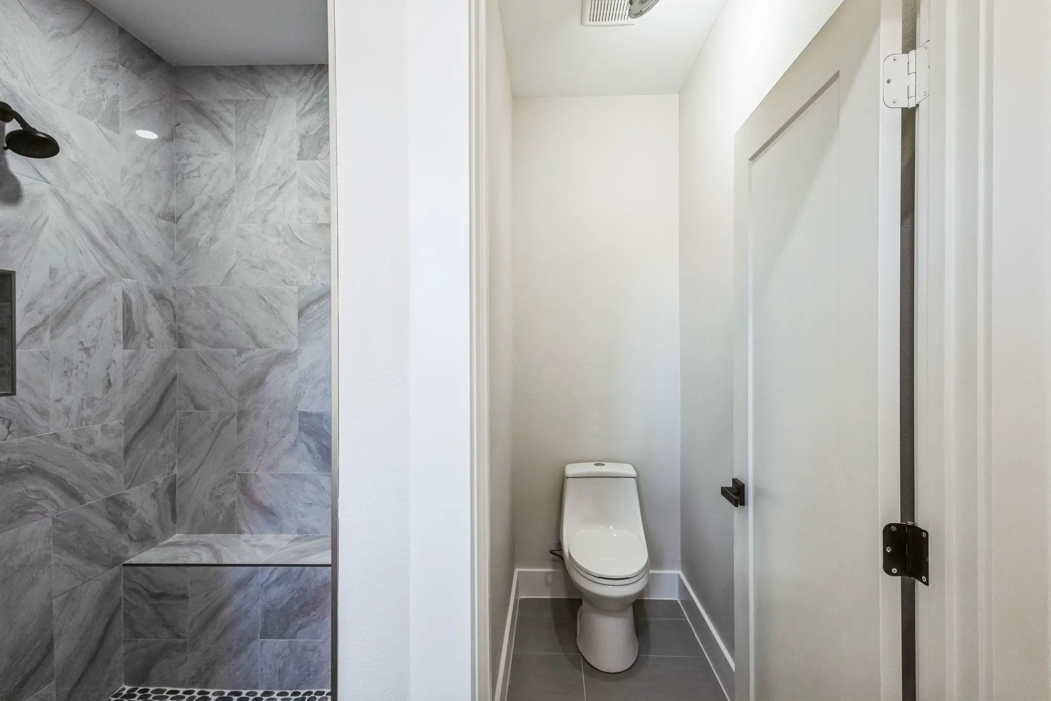 Bathroom with a tile shower, toilet, and tile patterned floors