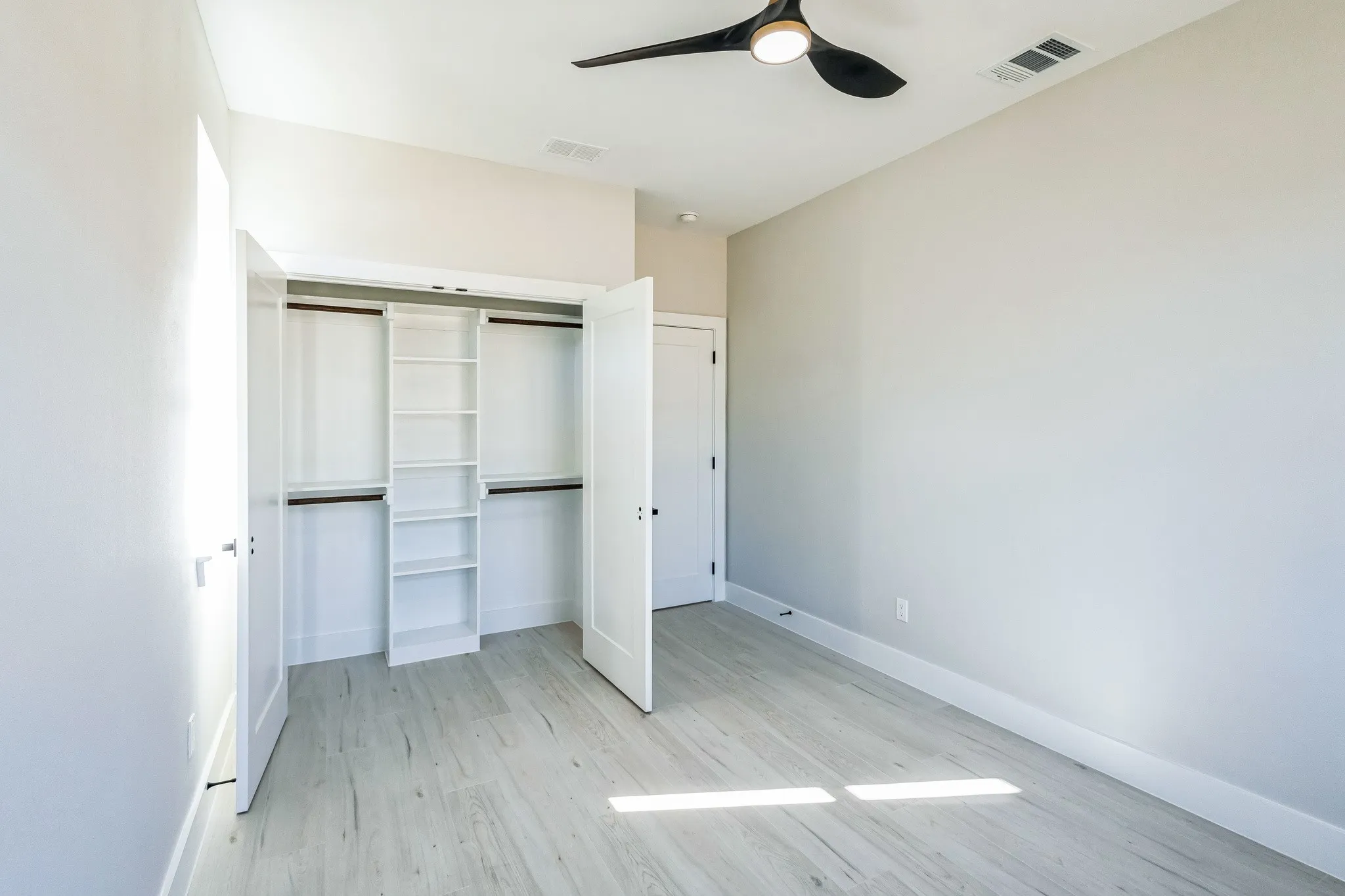 Unfurnished bedroom with ceiling fan, a closet, and light wood-type flooring