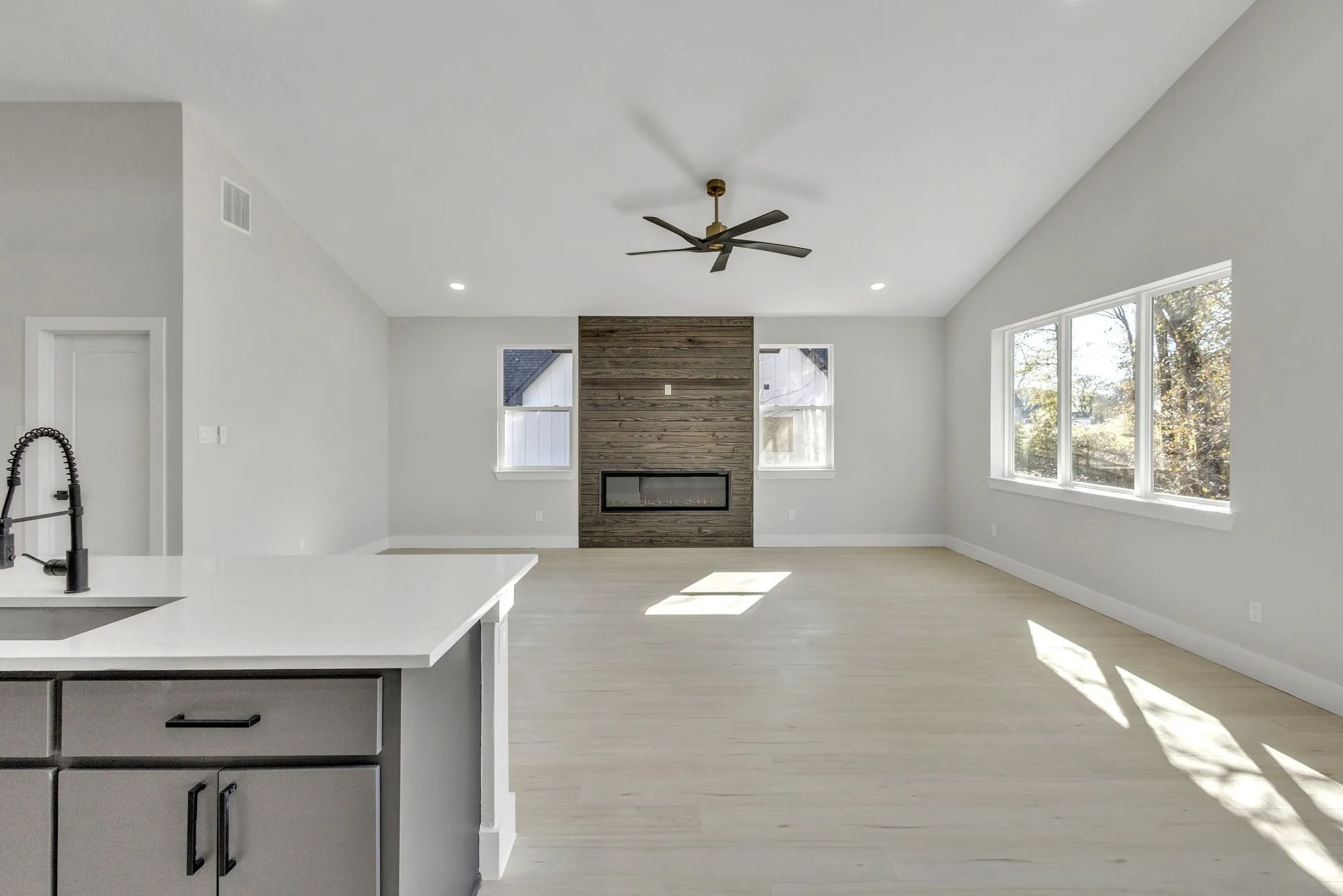 Kitchen featuring lofted ceiling, sink, a large fireplace, light wood-type flooring, and ceiling fan