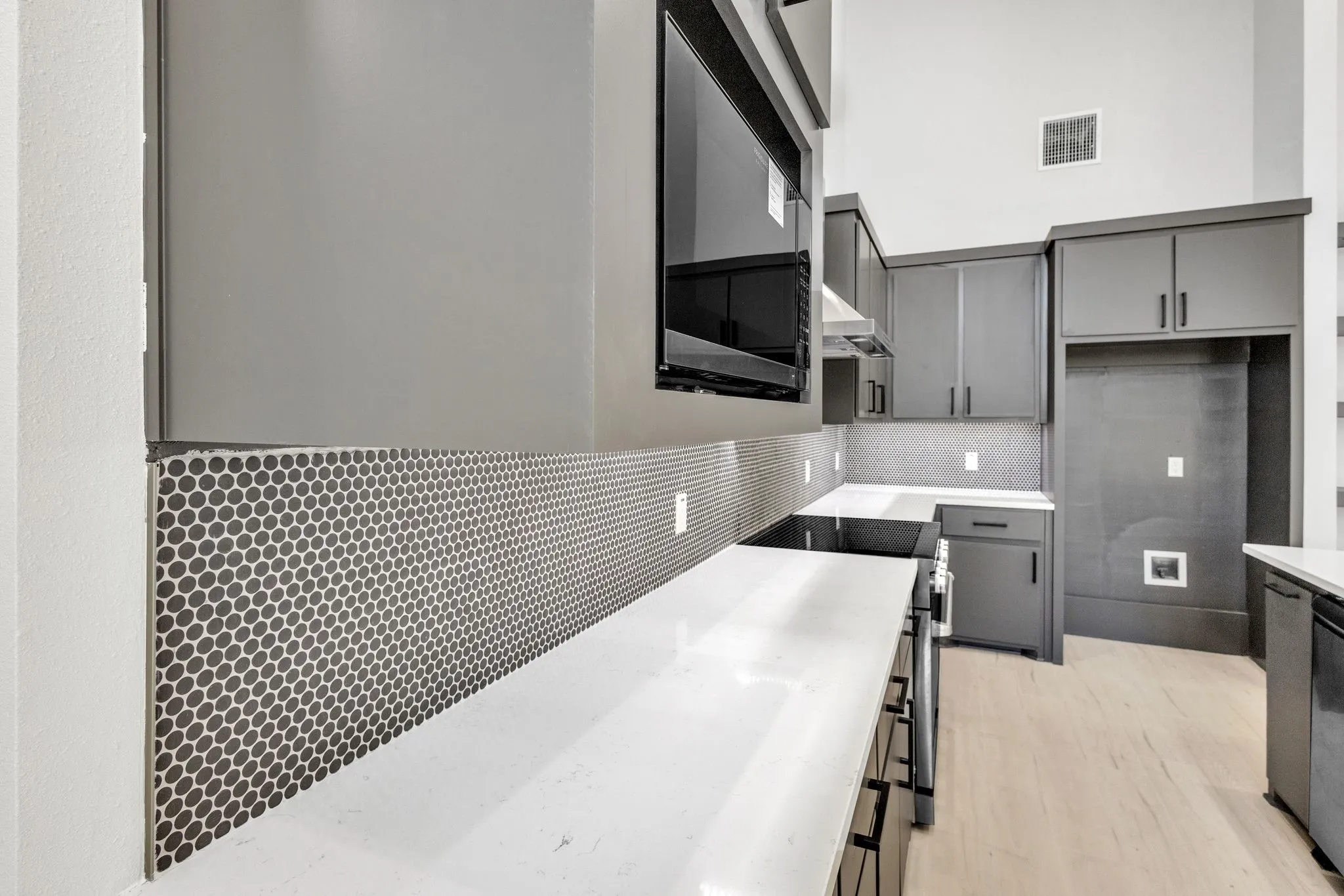 Kitchen featuring light wood-type flooring, wall chimney exhaust hood, tasteful backsplash, and gray cabinets