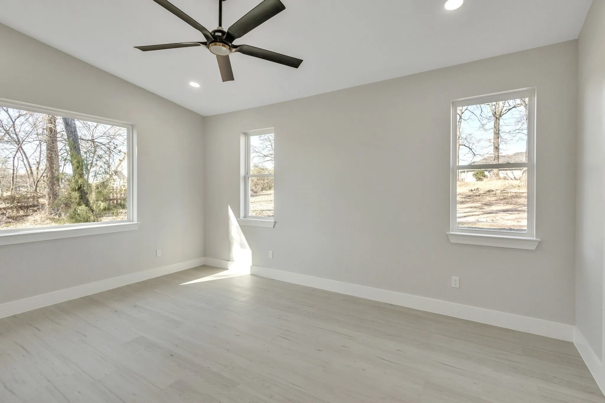 Empty room with light hardwood / wood-style floors, lofted ceiling, ceiling fan, and a healthy amount of sunlight