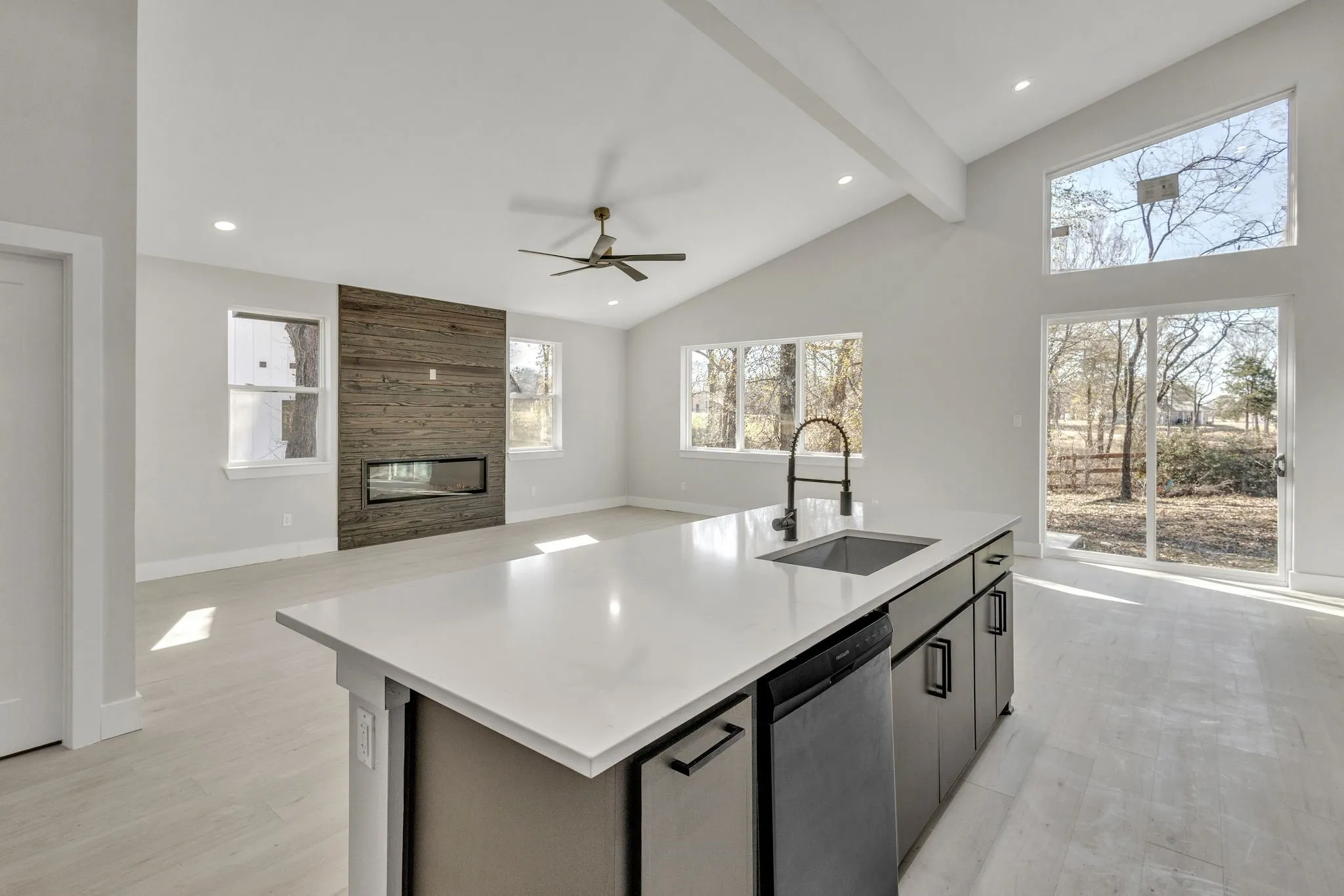 Kitchen with beamed ceiling, a tile fireplace, stainless steel dishwasher, sink, and a center island with sink