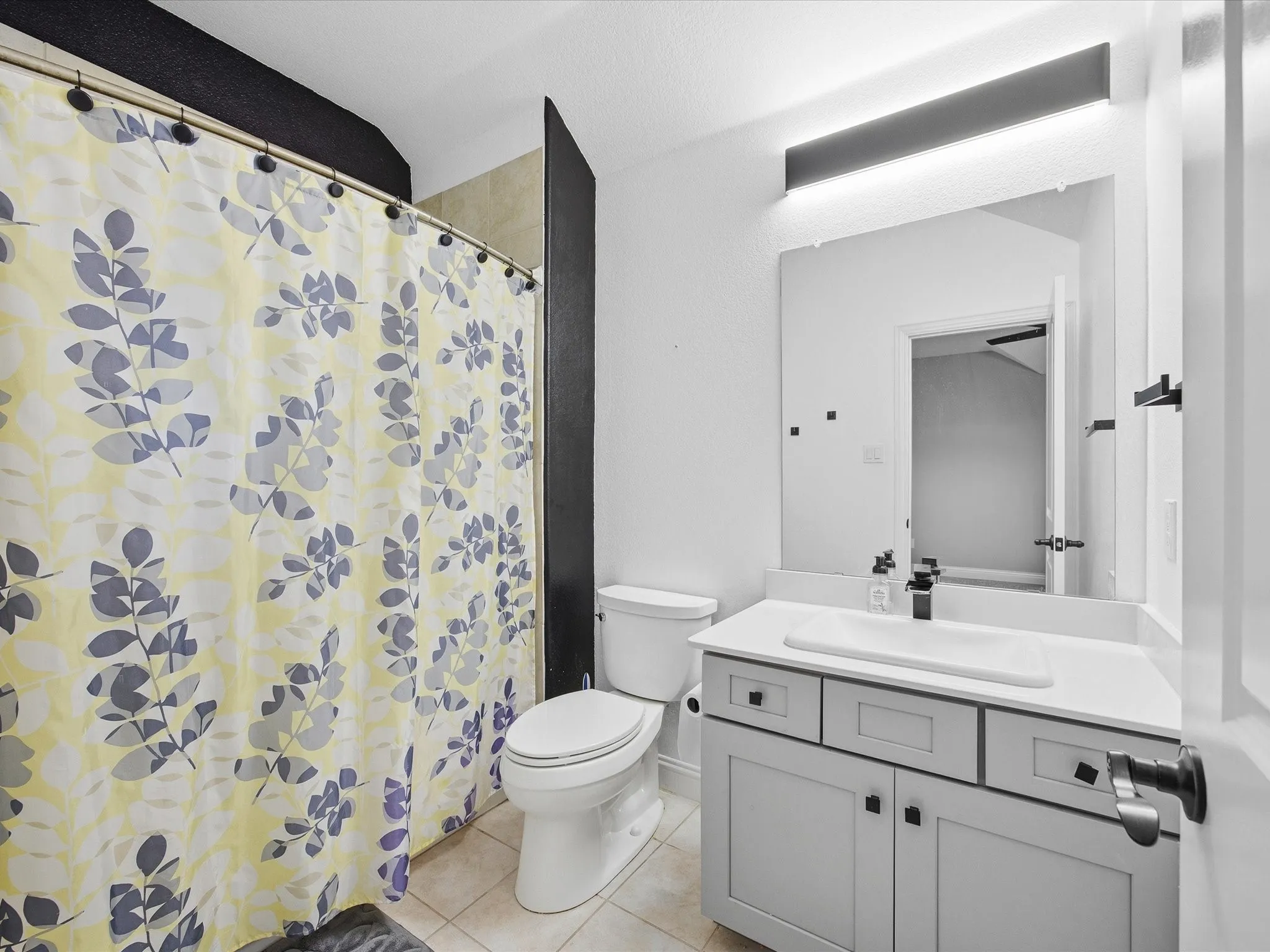 Full bath featuring vanity, a shower with curtain, and light tile patterned flooring