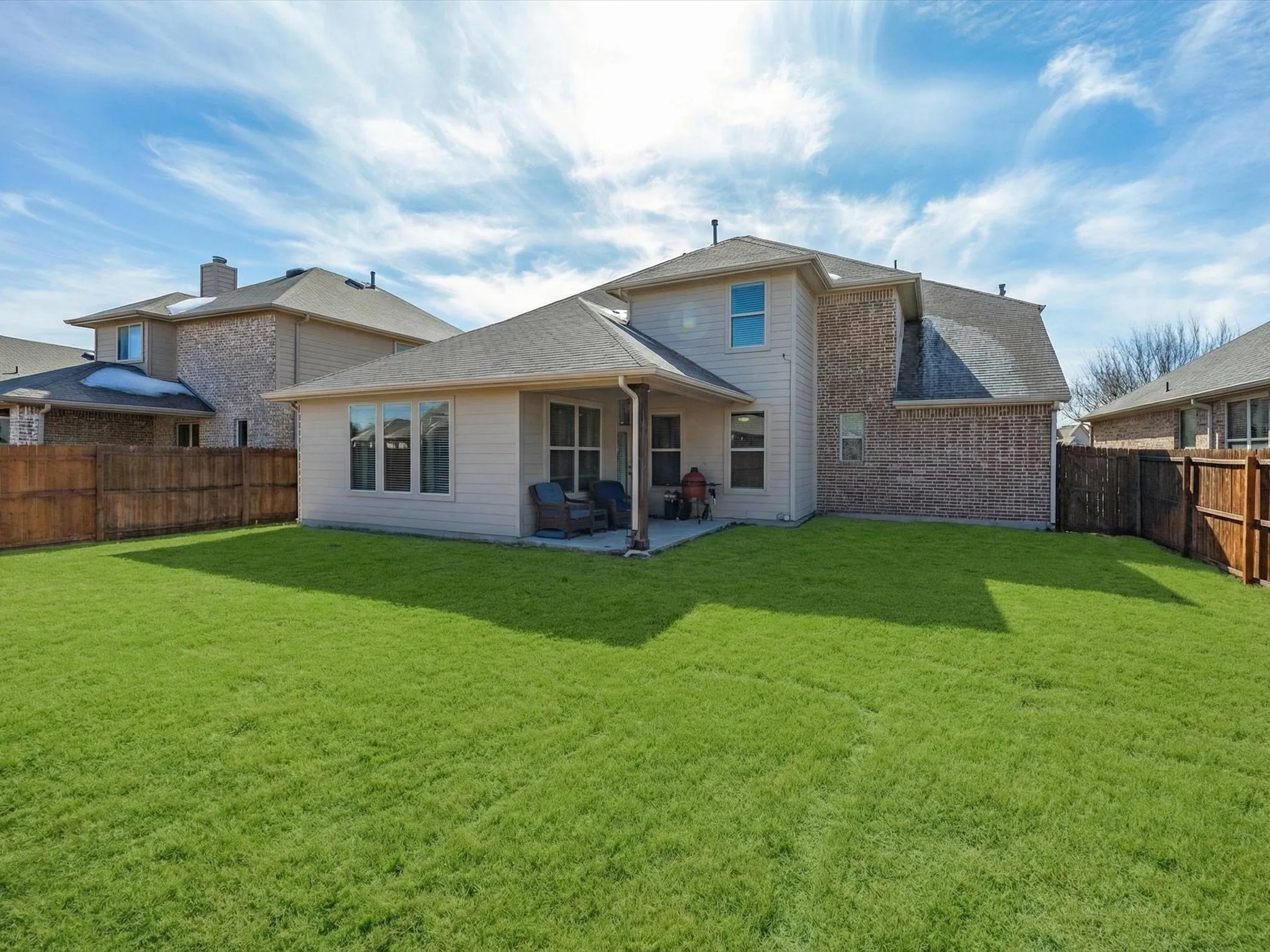 Rear view of property featuring a patio area, a fenced backyard, roof with shingles, and brick siding