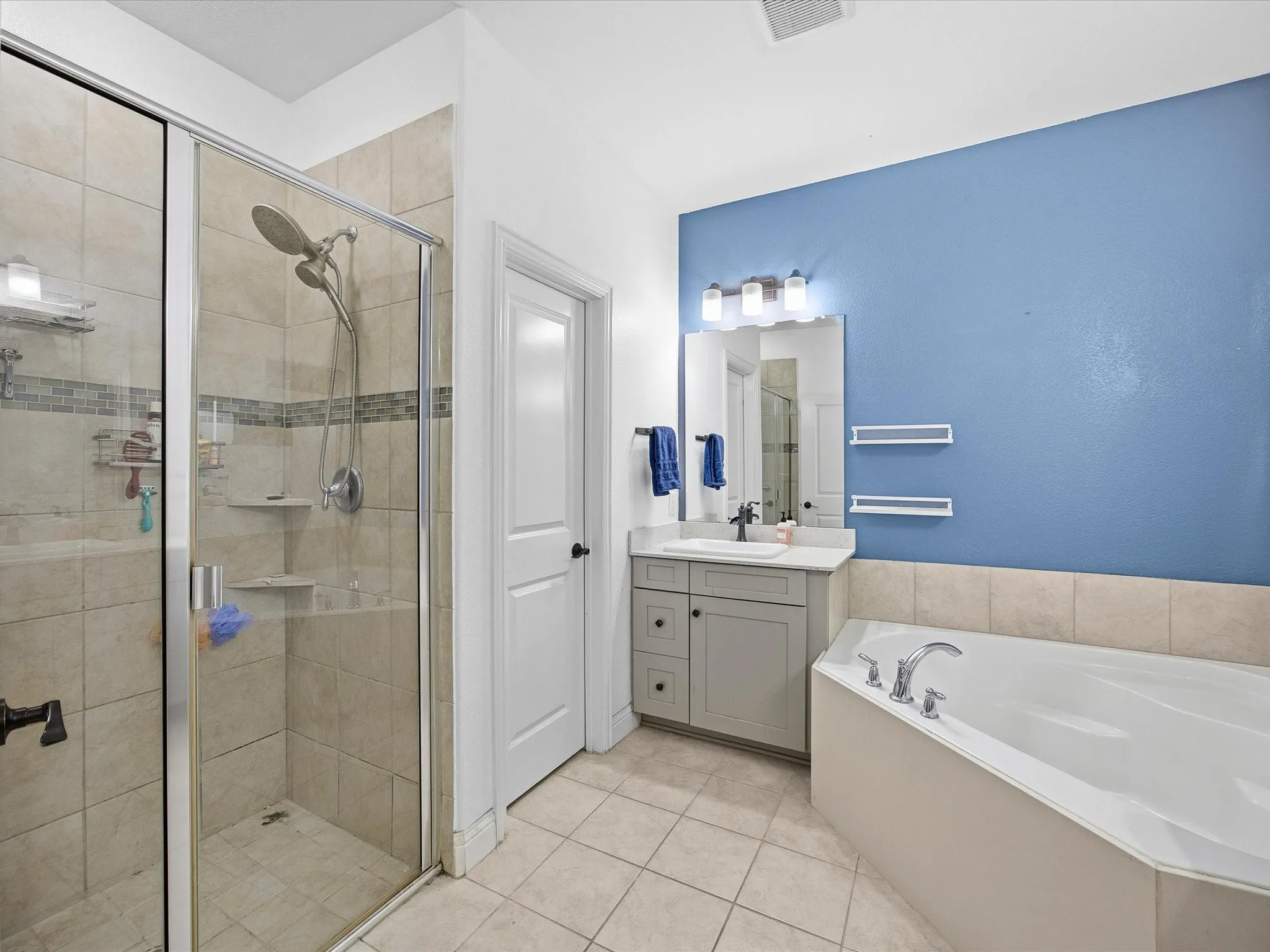 Primary bathroom with a stall shower, a bath, vanity, and light tile patterned floors