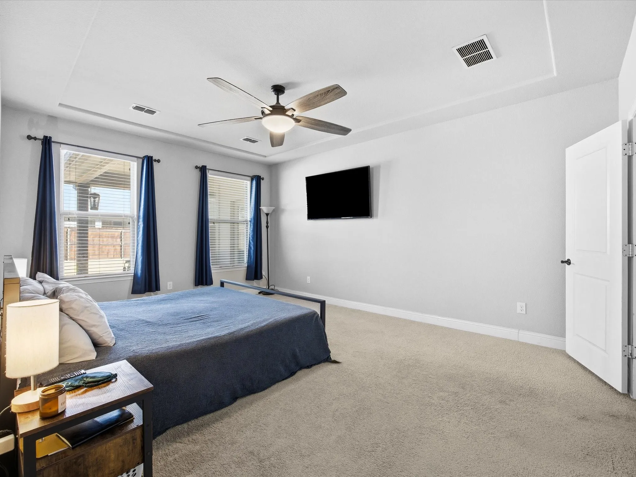 Carpeted primary bedroom with ceiling fan and baseboards