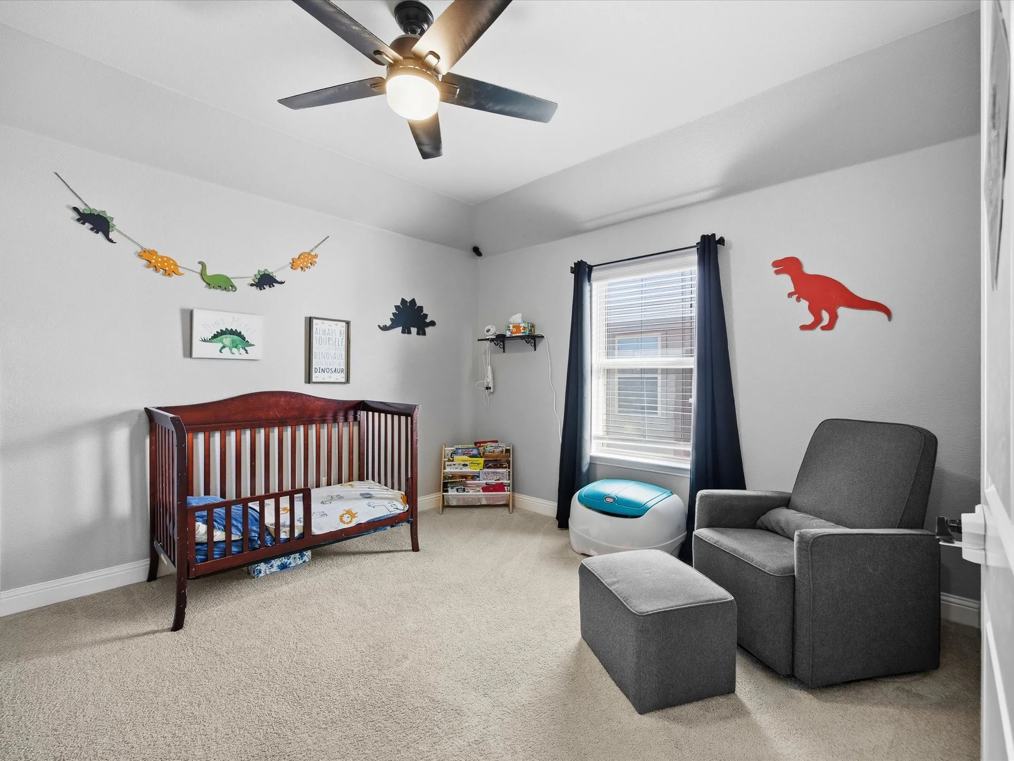 Bedroom with a crib, light colored carpet, ceiling fan, and vaulted ceiling
