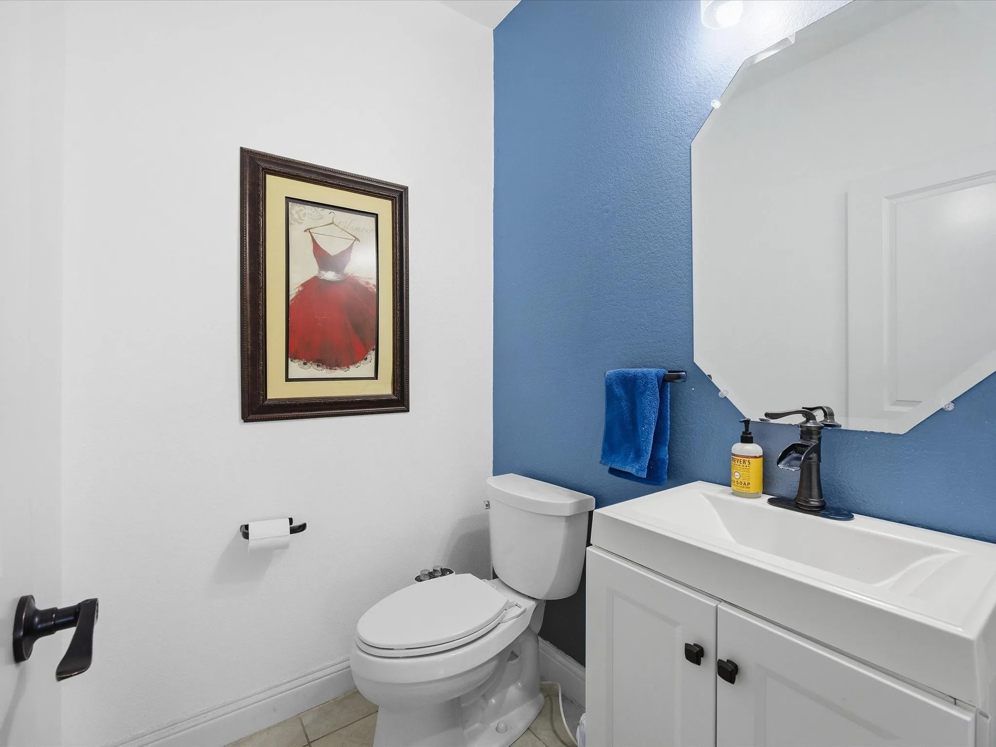 Half bathroom with vanity and light tile patterned flooring
