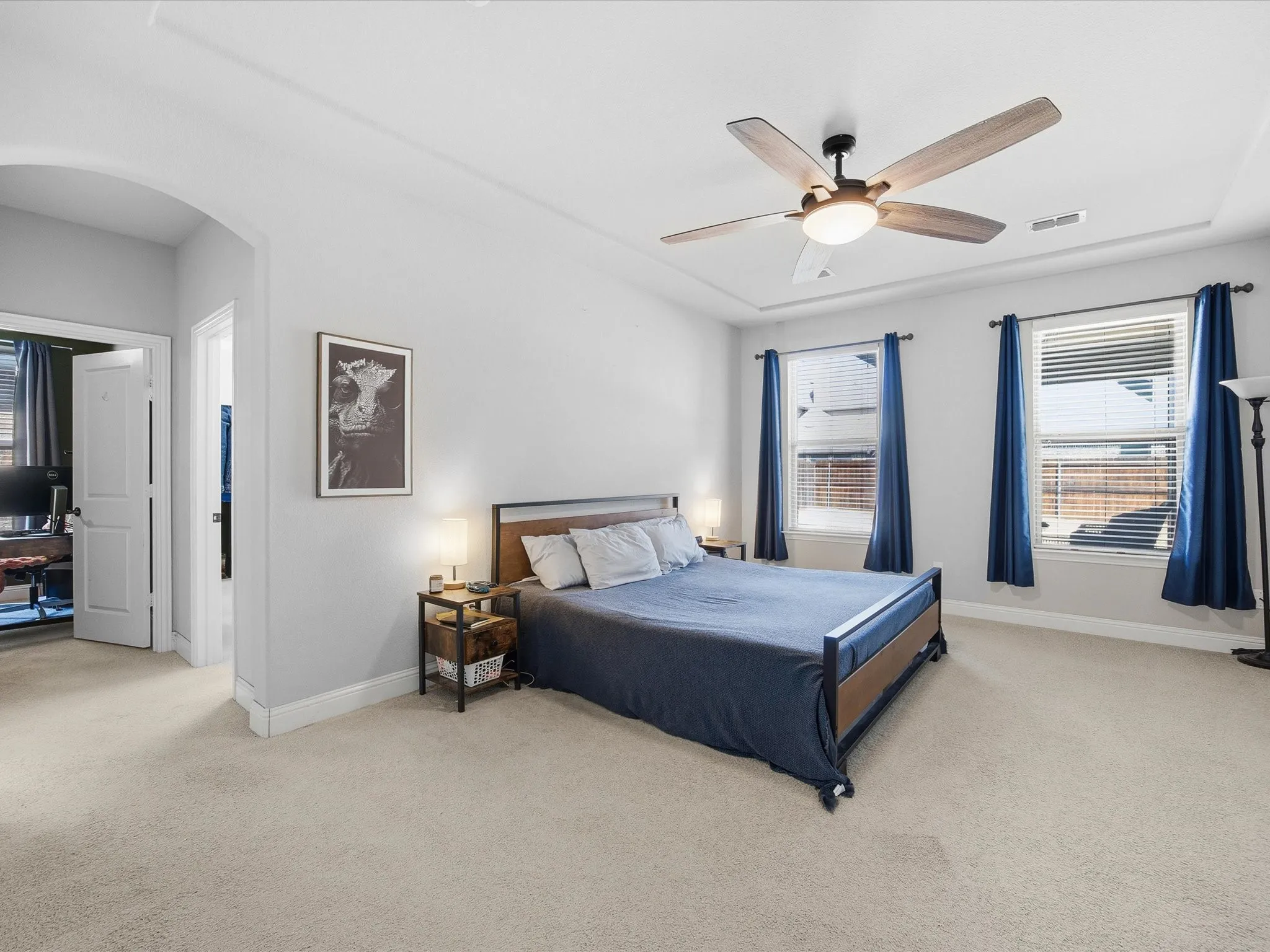 Primary Bedroom with arched walkways, light colored carpet, and ceiling fan