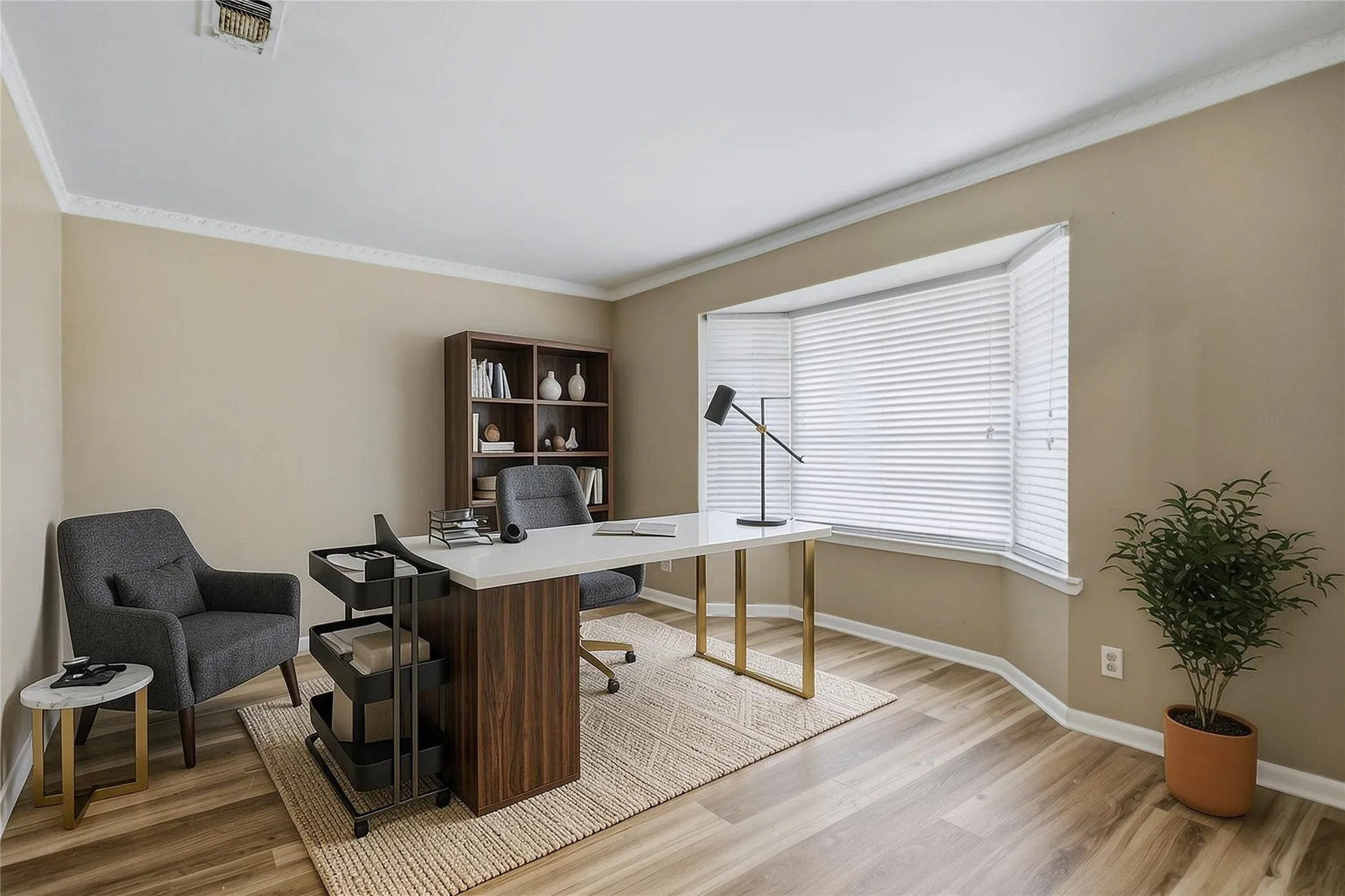Virtual staged Bay window with white blinds, crown molding, light wood-finish flooring, and a built-in shelving unit