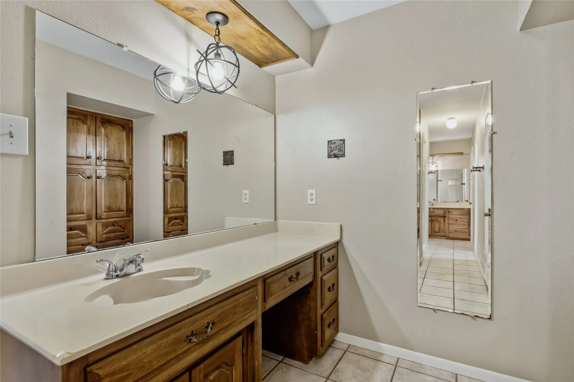 Spacious vanity featuring a large integrated sink, wood cabinetry, and an expansive wall-mounted mirror