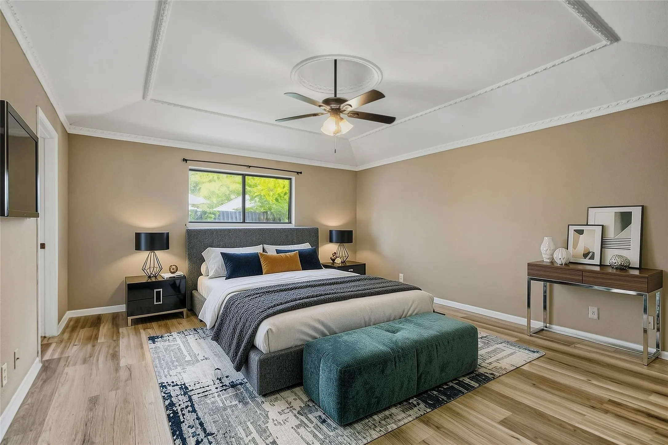 Virtual staged Tray ceiling with decorative molding, ceiling fan, wood-finish flooring, and a large window