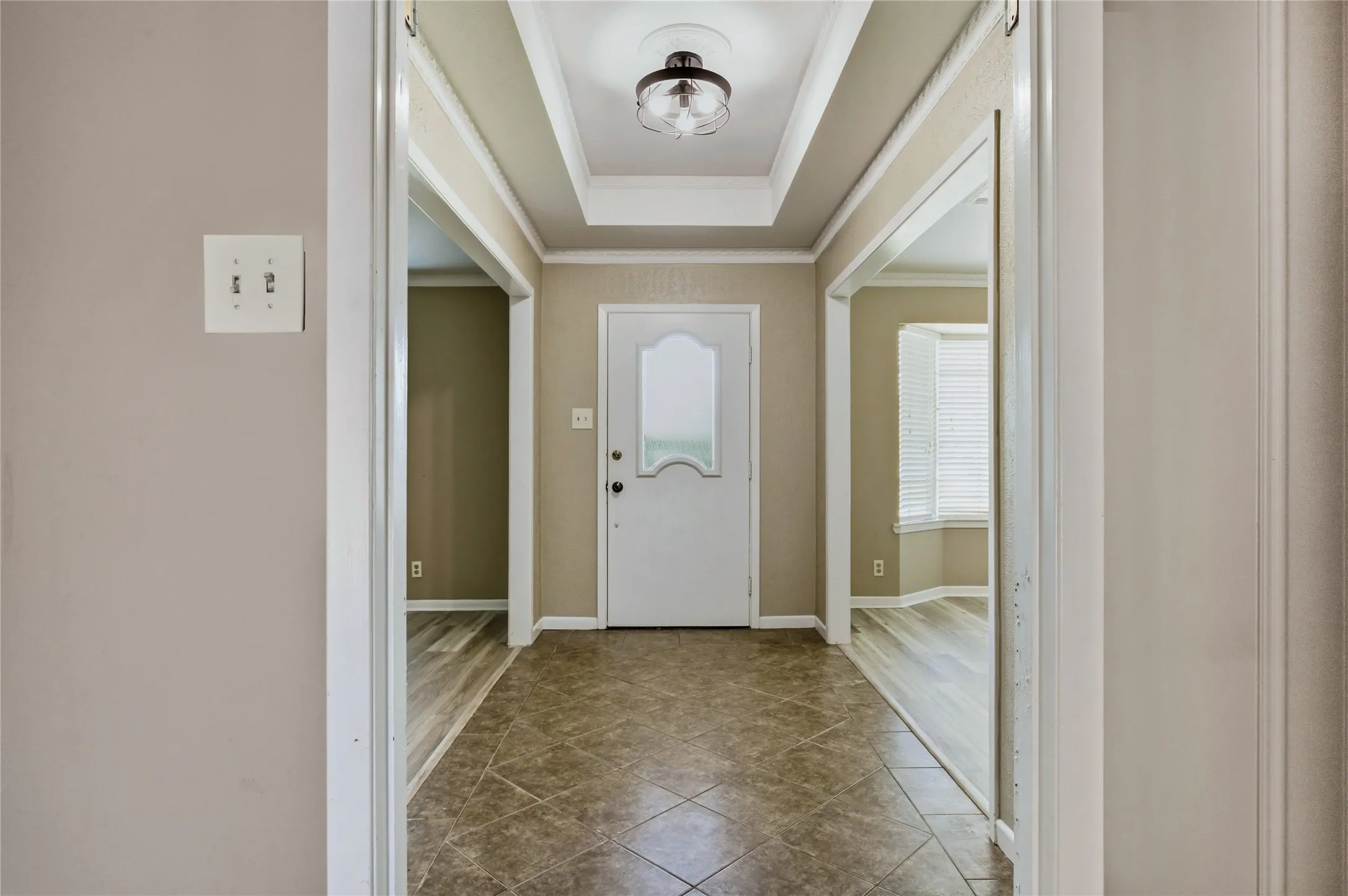 Foyer featuring a tray ceiling, a semi-flush mount light fixture, tile flooring, and a white entry door with frosted glass