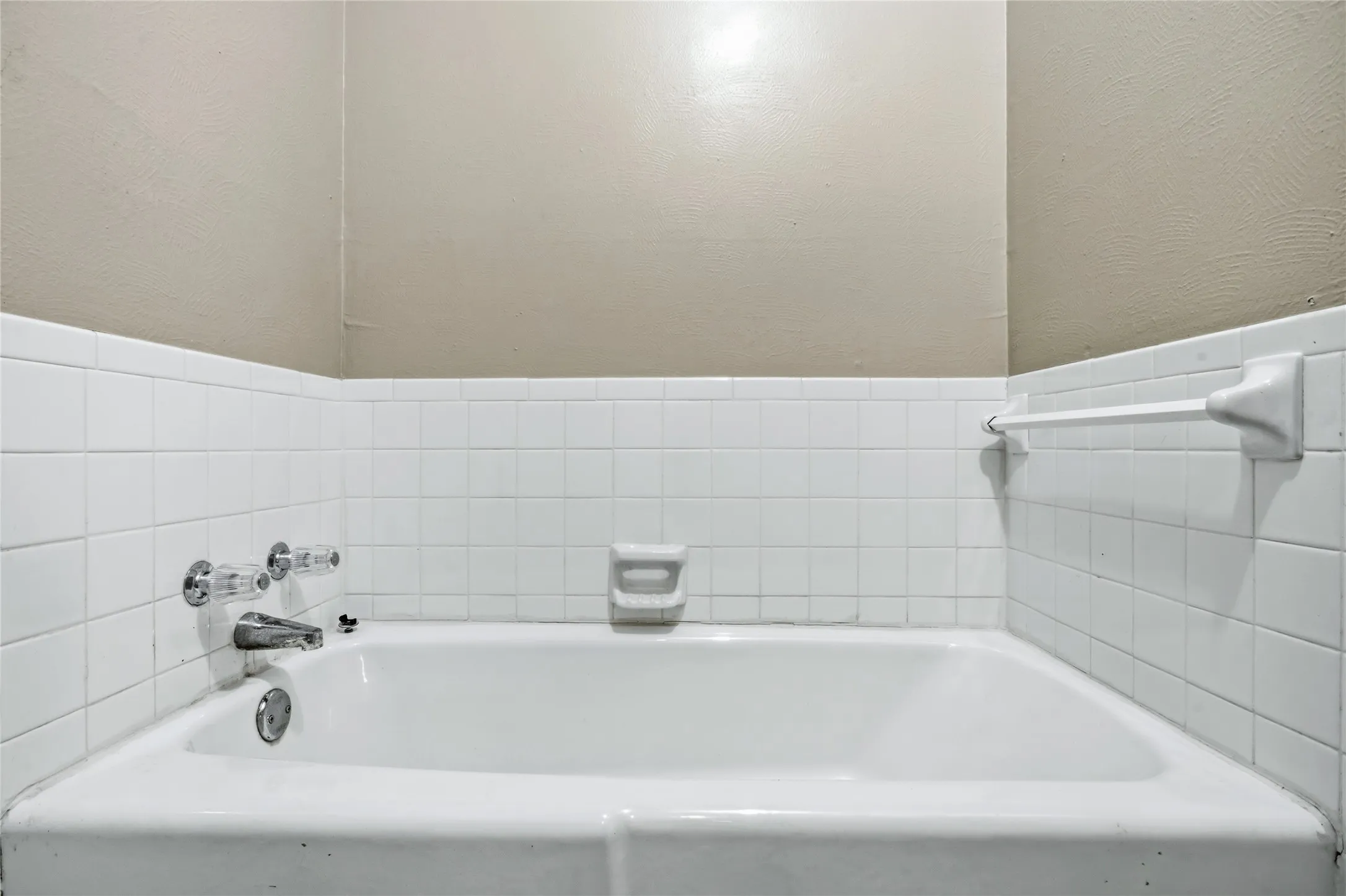 Bathtub with white tile surround and wall-mounted faucet