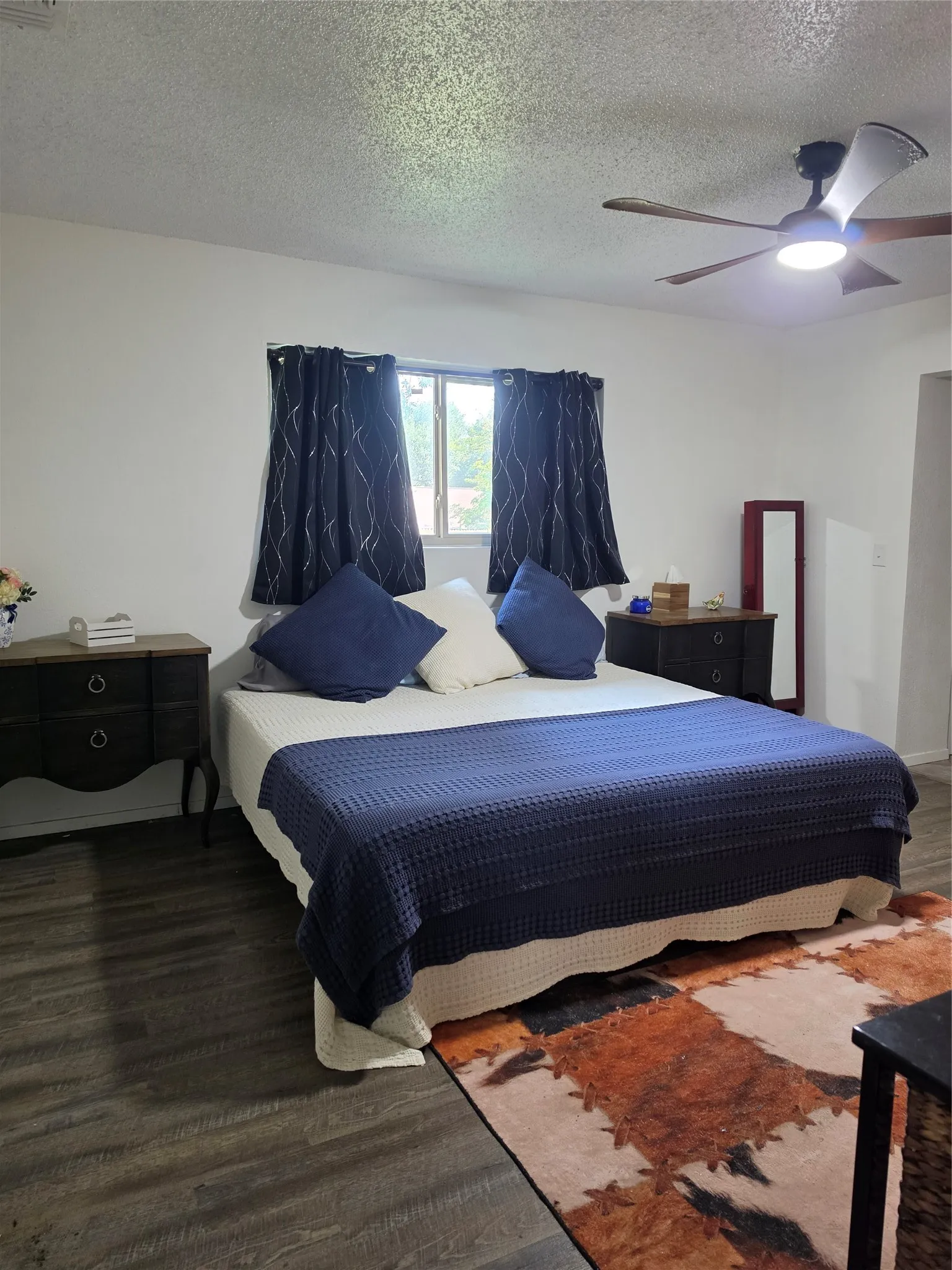 Spacious room featuring wood-finish flooring, a ceiling fan with integrated lighting, and multiple windows