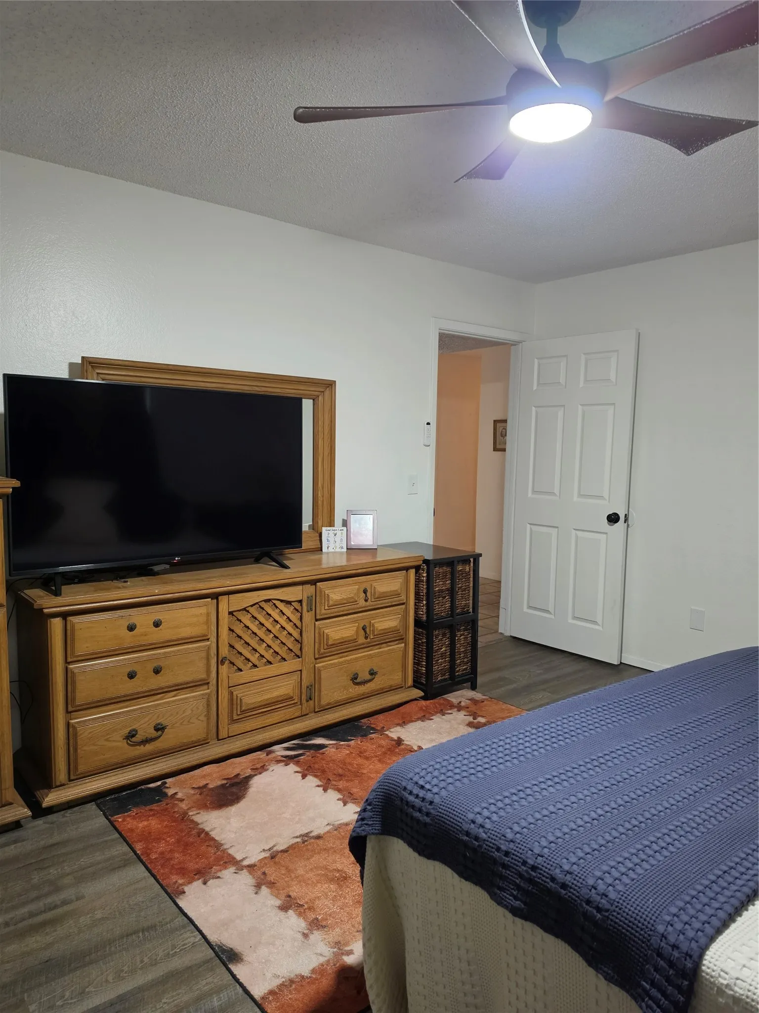 Bright interior featuring a ceiling fan with integrated lighting, wood-finish flooring, and a white paneled door
