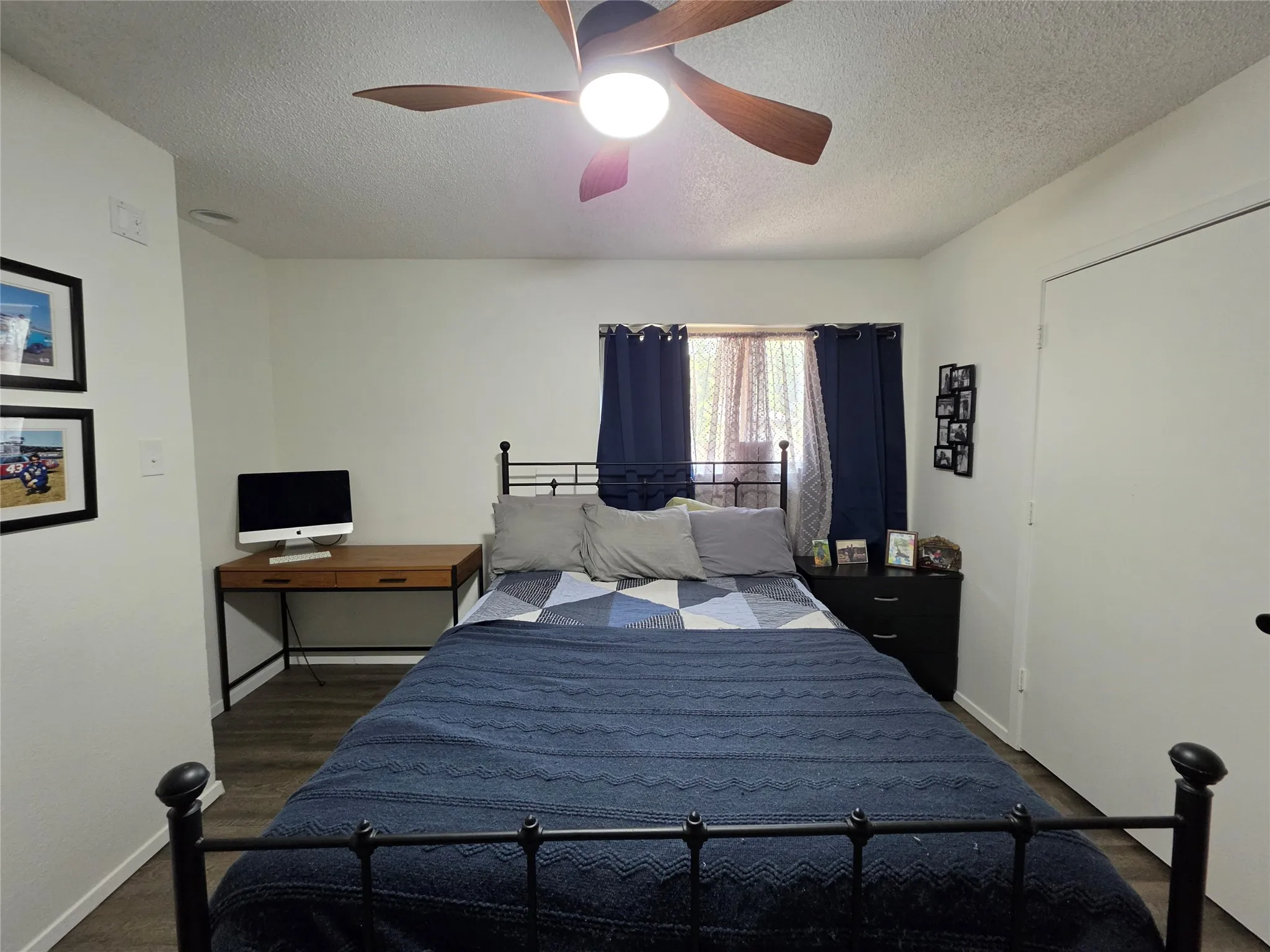 Bedroom featuring wood-finish flooring, a ceiling fan with integrated lighting, and a window with existing curtain rods