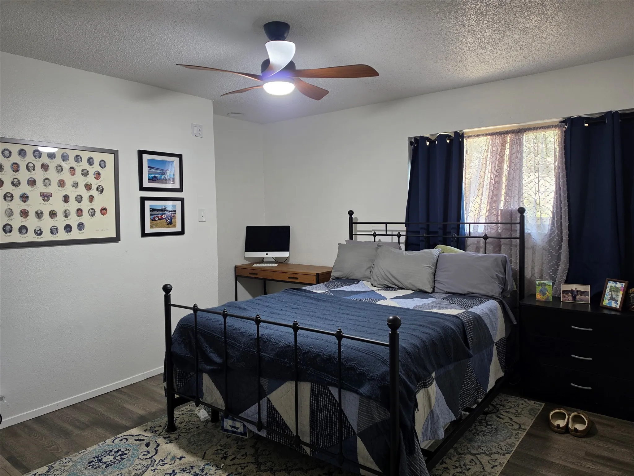 Interior room featuring wood-finish flooring, white walls, and a ceiling fan with integrated lighting