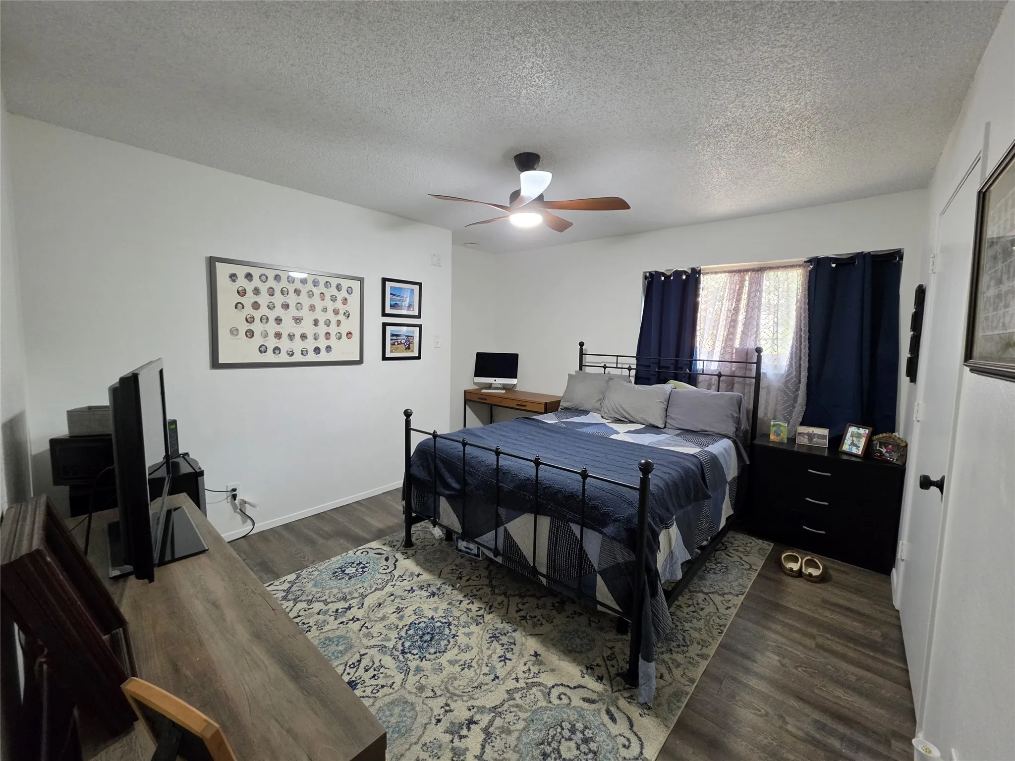 Room featuring wood-finish flooring, a ceiling fan with integrated lighting, and white painted walls