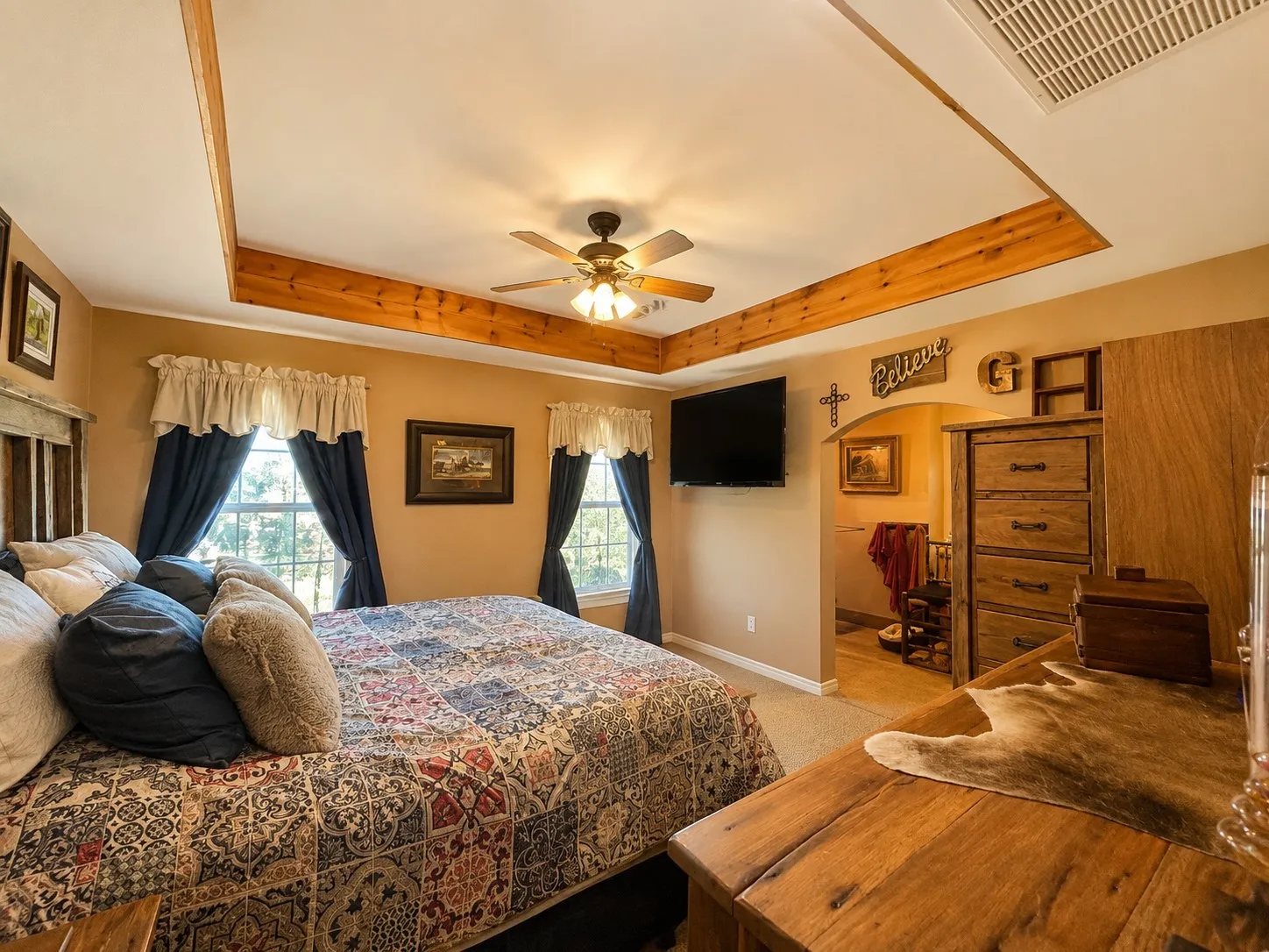 Tray ceiling with wood beam accents and a ceiling fan