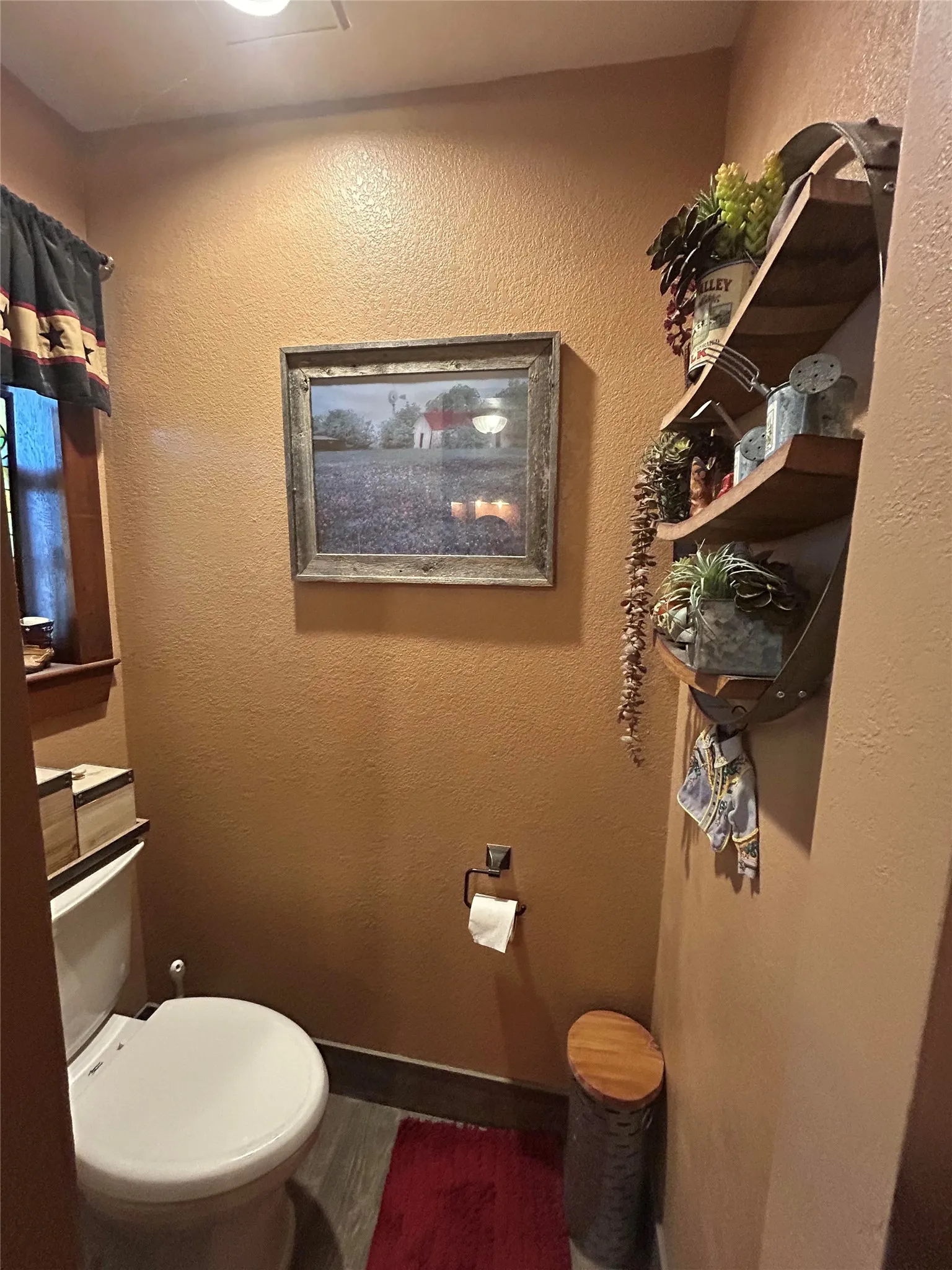 Powder room featuring textured walls, wood-finish flooring, and a built-in multi-tiered display shelf