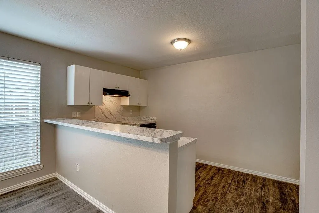 Kitchen with a breakfast bar featuring a white marble-look countertop and backsplash