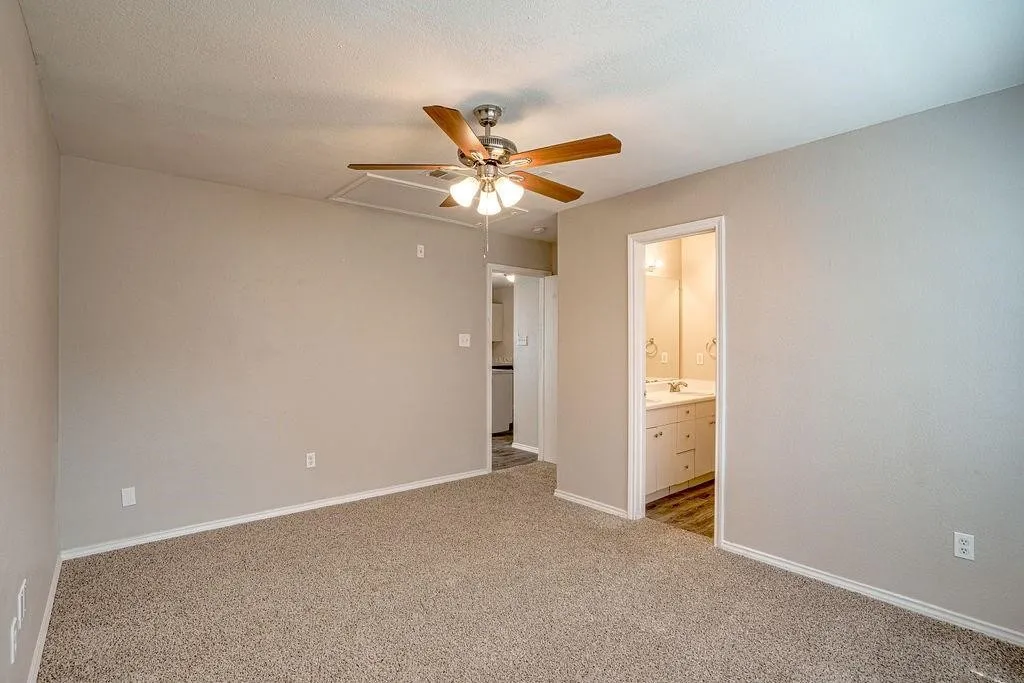 Carpeted interior space featuring a ceiling fan with integrated lighting, neutral wall tones, and white baseboards